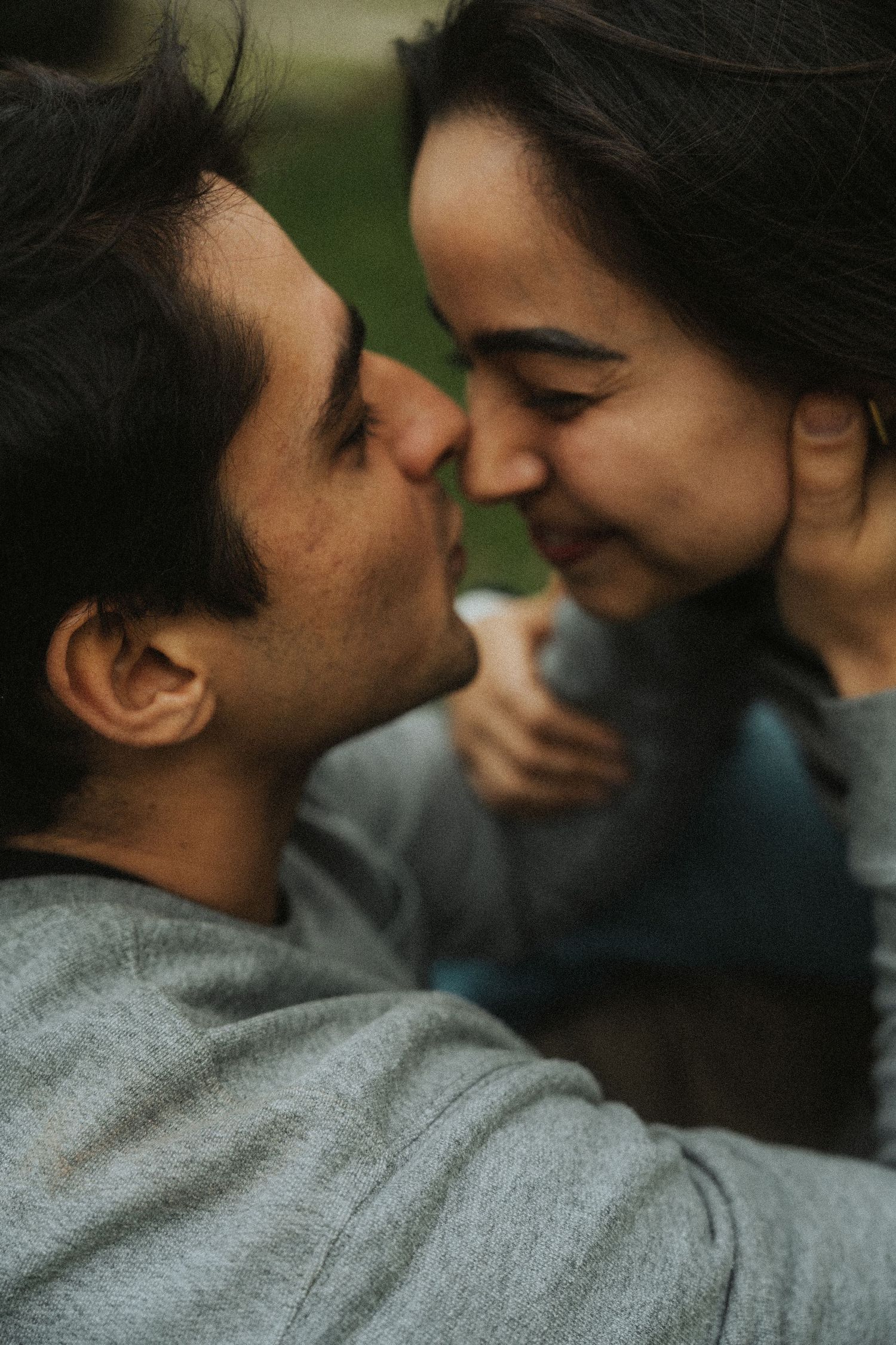 A close-up intimate moment between a couple in gray sweaters sharing a tender smile together.