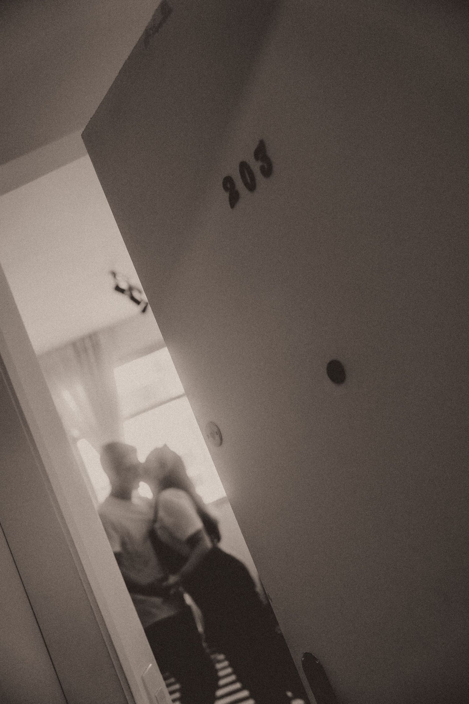 A sequence of grainy black and white security camera footage showing shadowy figures in a doorway at night.