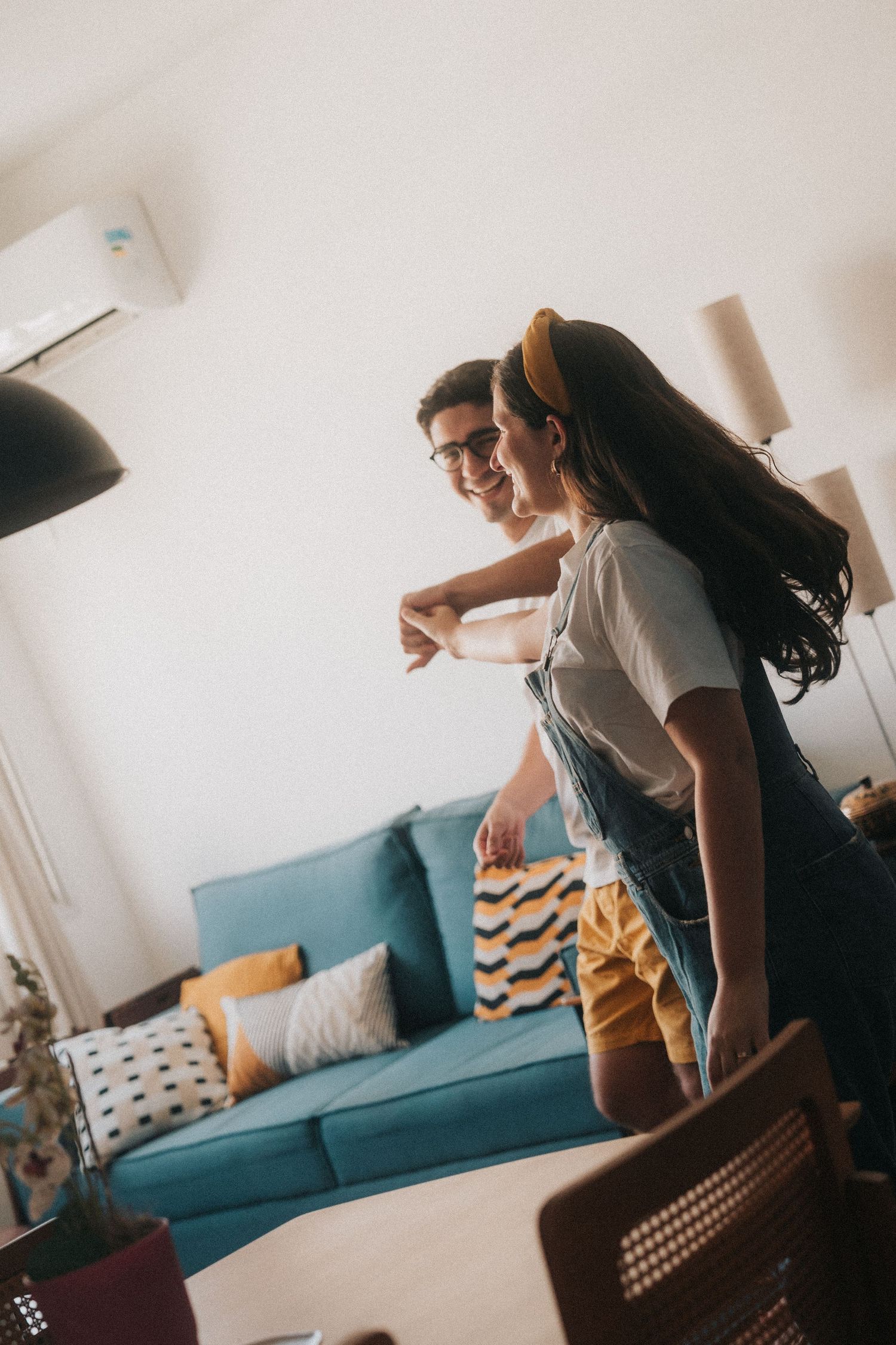 A couple dancing together in their cozy living room with a blue couch and decorative pillows in the background.