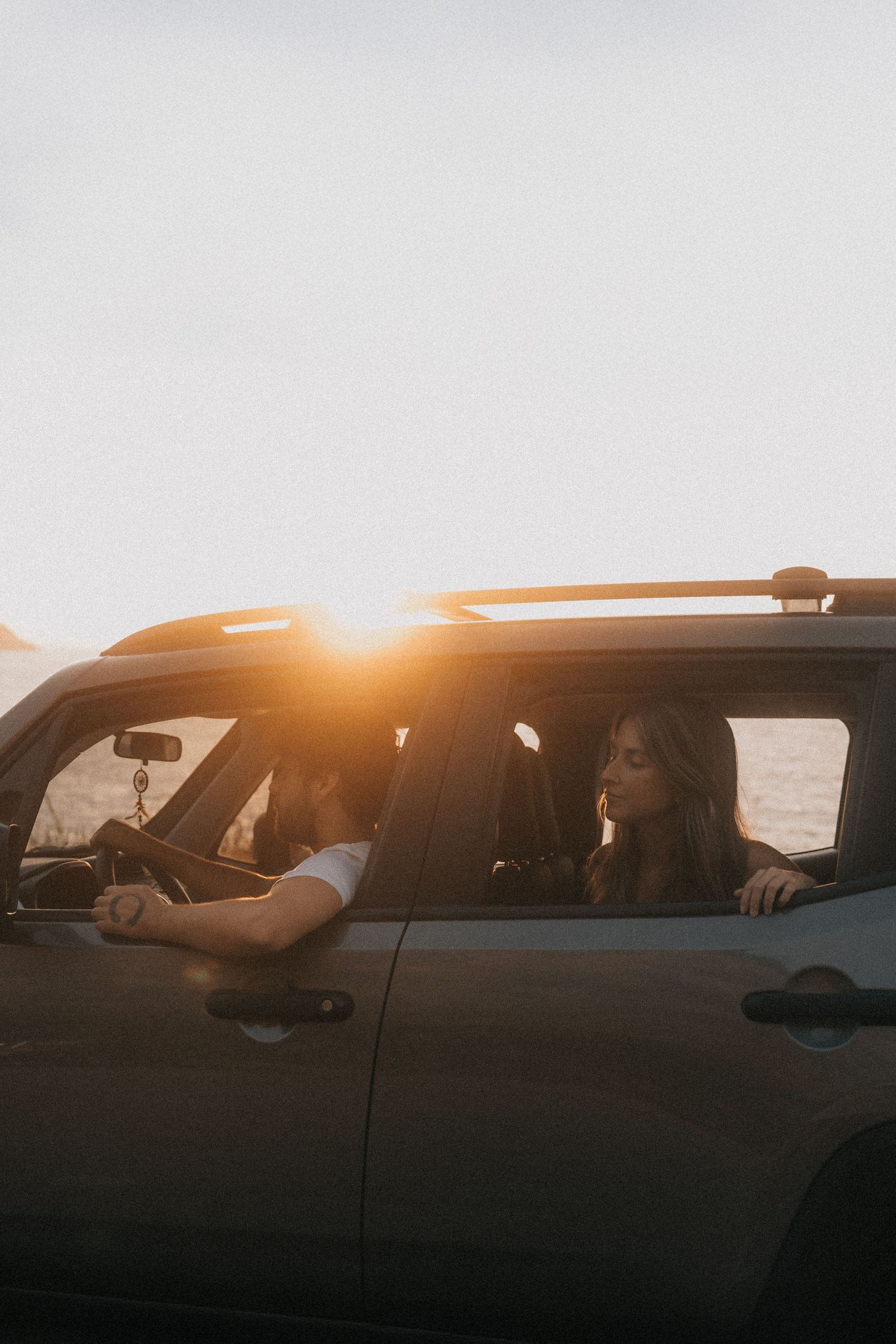 Silhouettes of passengers visible through car windows at sunset with warm golden light streaming in.