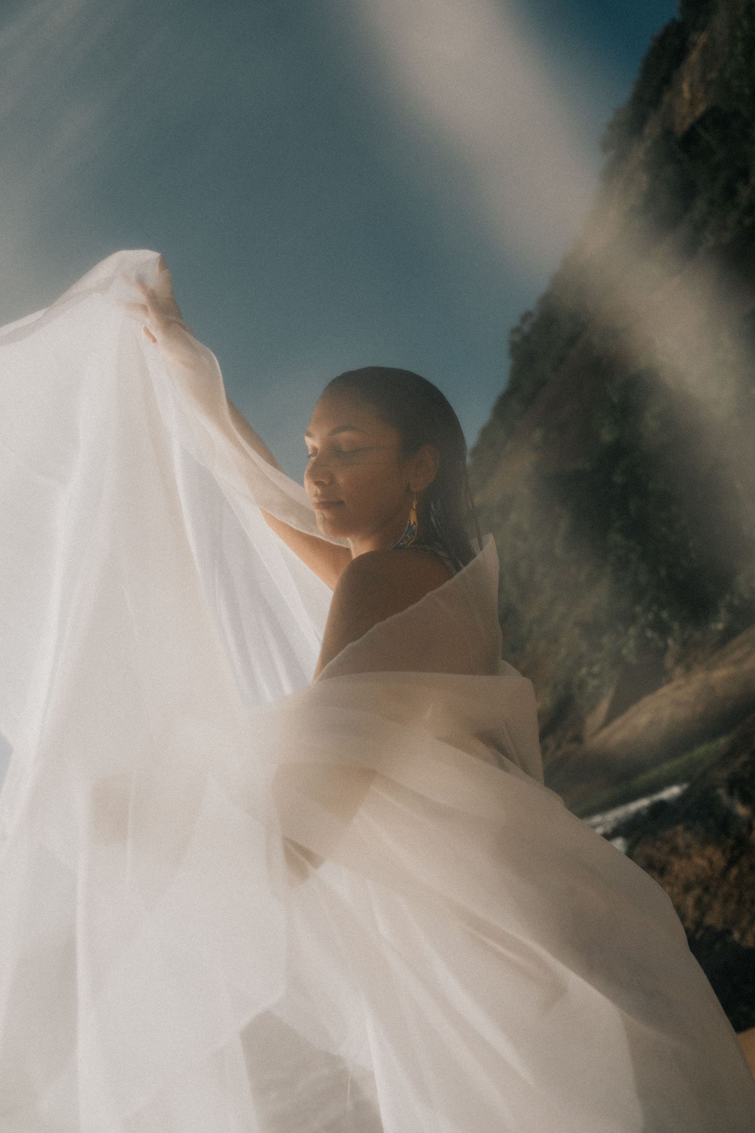 Ethereal bridal veil blowing in the wind against a misty dark background creating a romantic silhouette.