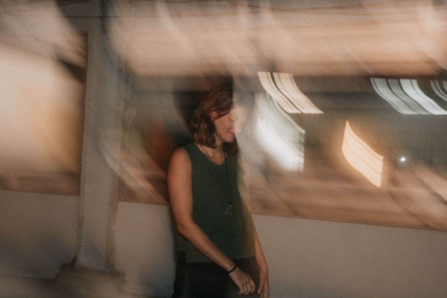 A soft motion blur photo shows an abstract view of someone in black moving past a neutral-toned background.