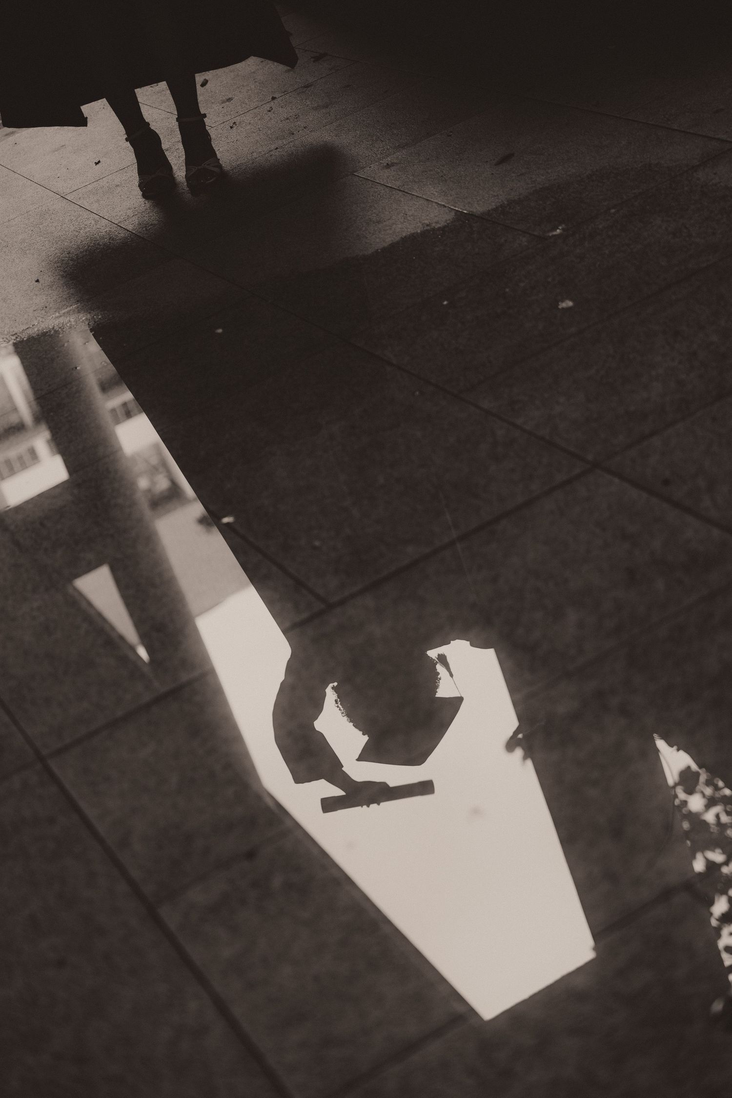 Black and white photo sequence showing feet walking through patches of light on a dark concrete sidewalk.