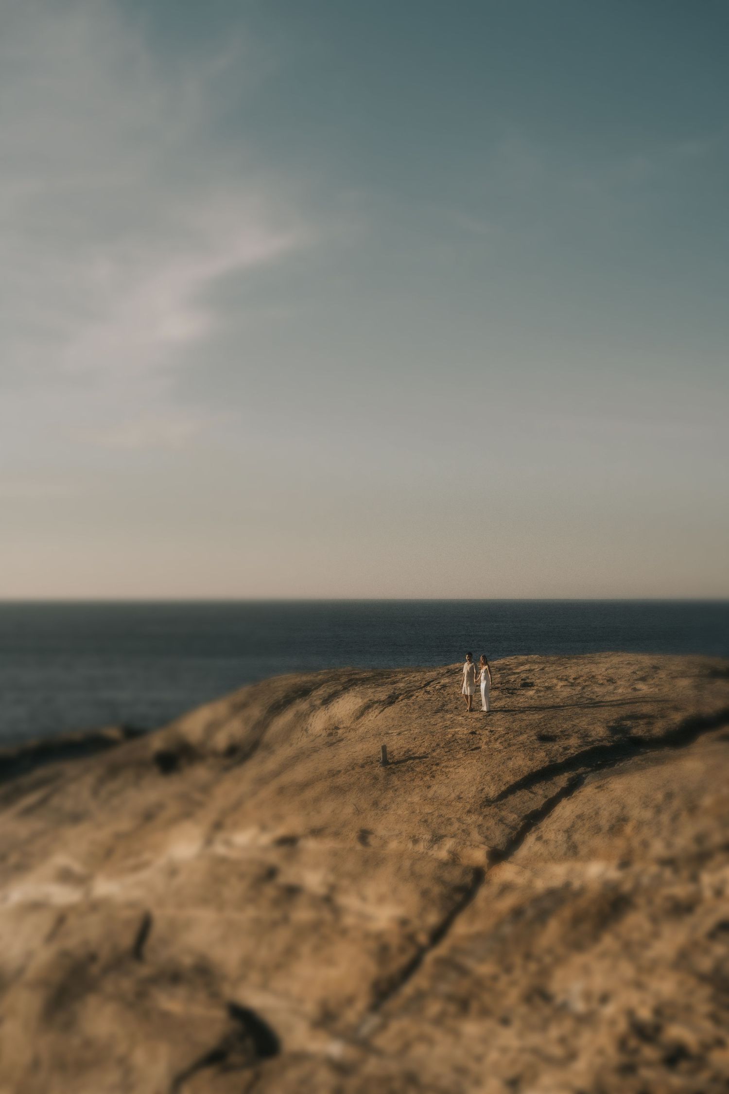 A rugged desert coastline stretches under cloudy skies, creating a moody panoramic landscape.