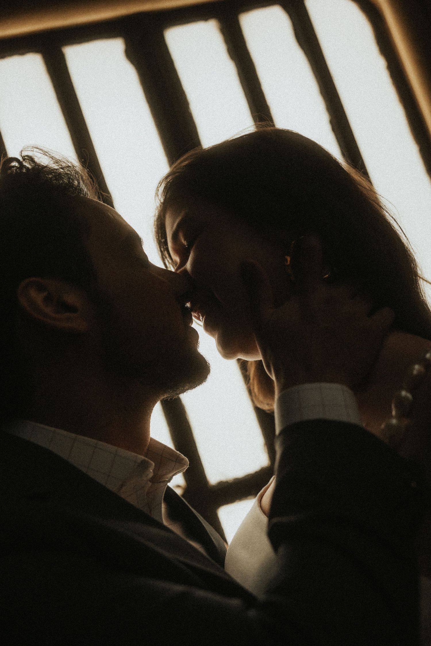 A silhouetted couple in a romantic moment against a bright window, creating a dramatic backlit effect.