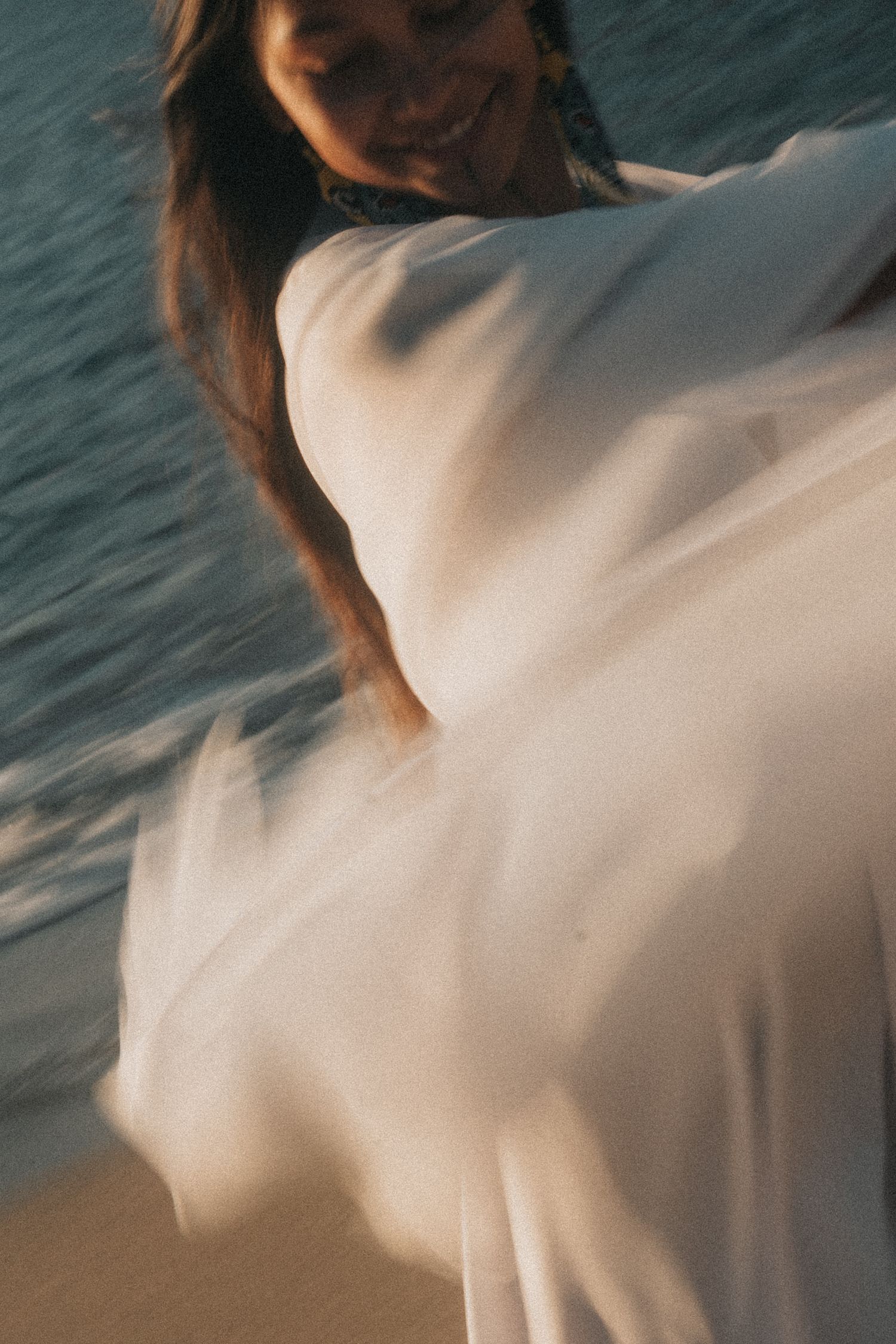 Abstract motion blur sequence of white fabric flowing against a dark teal ocean background.