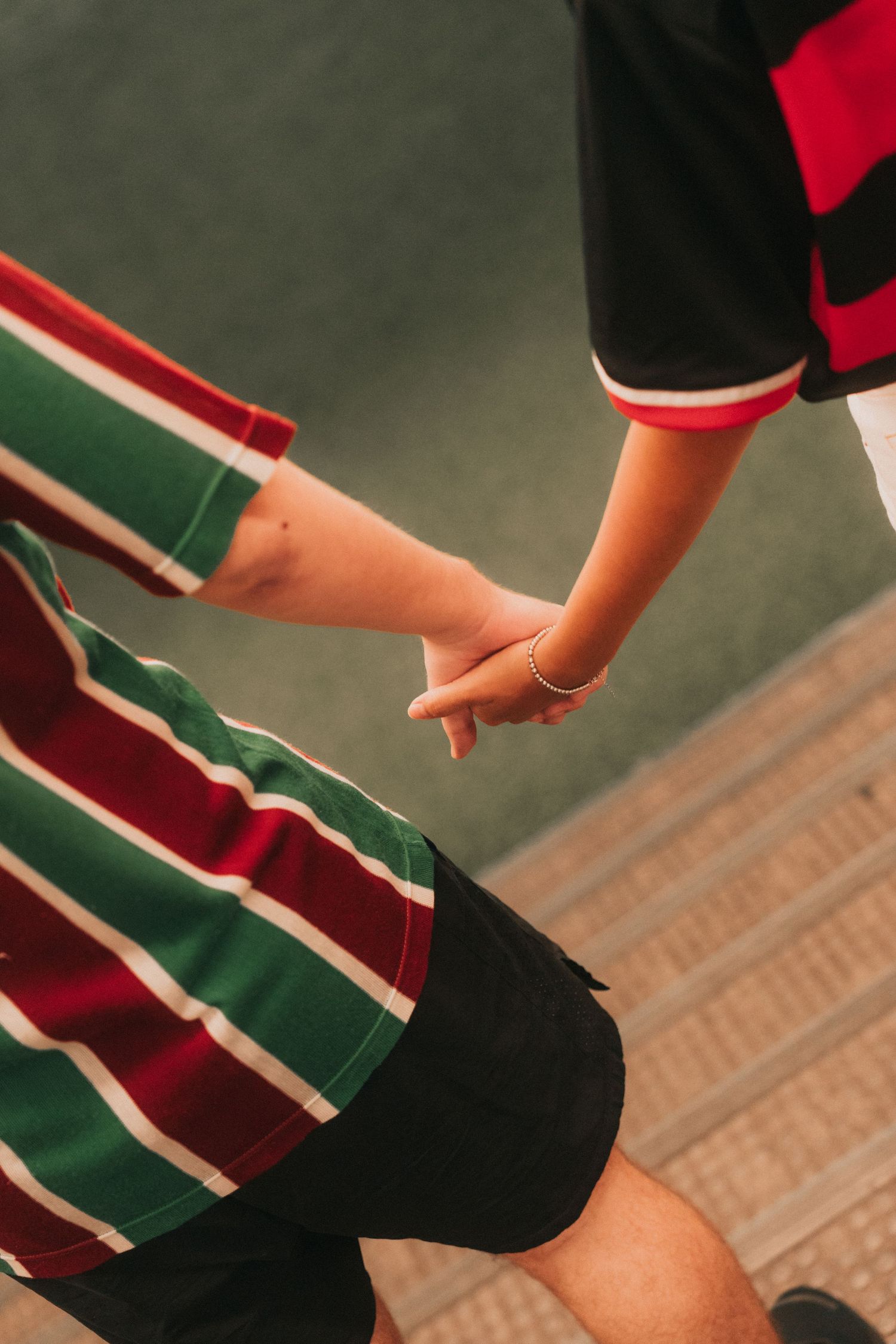 Close-up sequence of hands adjusting and rolling up red and black striped athletic socks against green fabric.