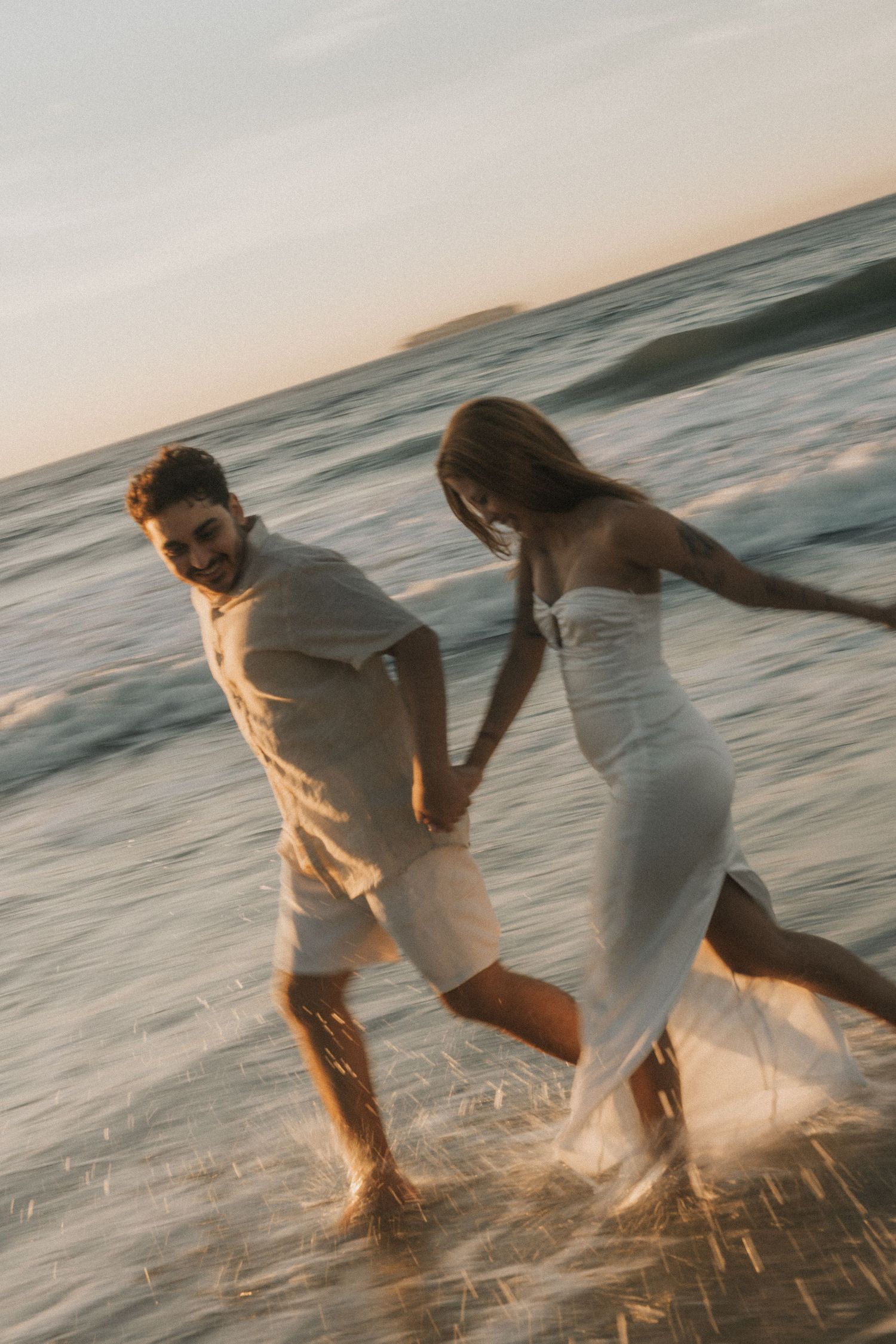 A multi-frame sequence showing someone kicking and splashing in shallow ocean water during golden hour lighting.