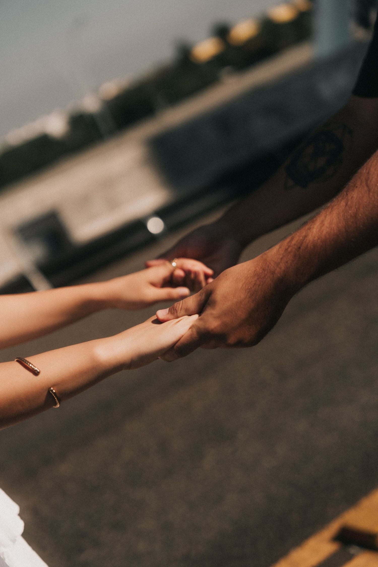 Close-up view of a light-skinned hand and dark-skinned hand clasped together in unity against a blurred background.