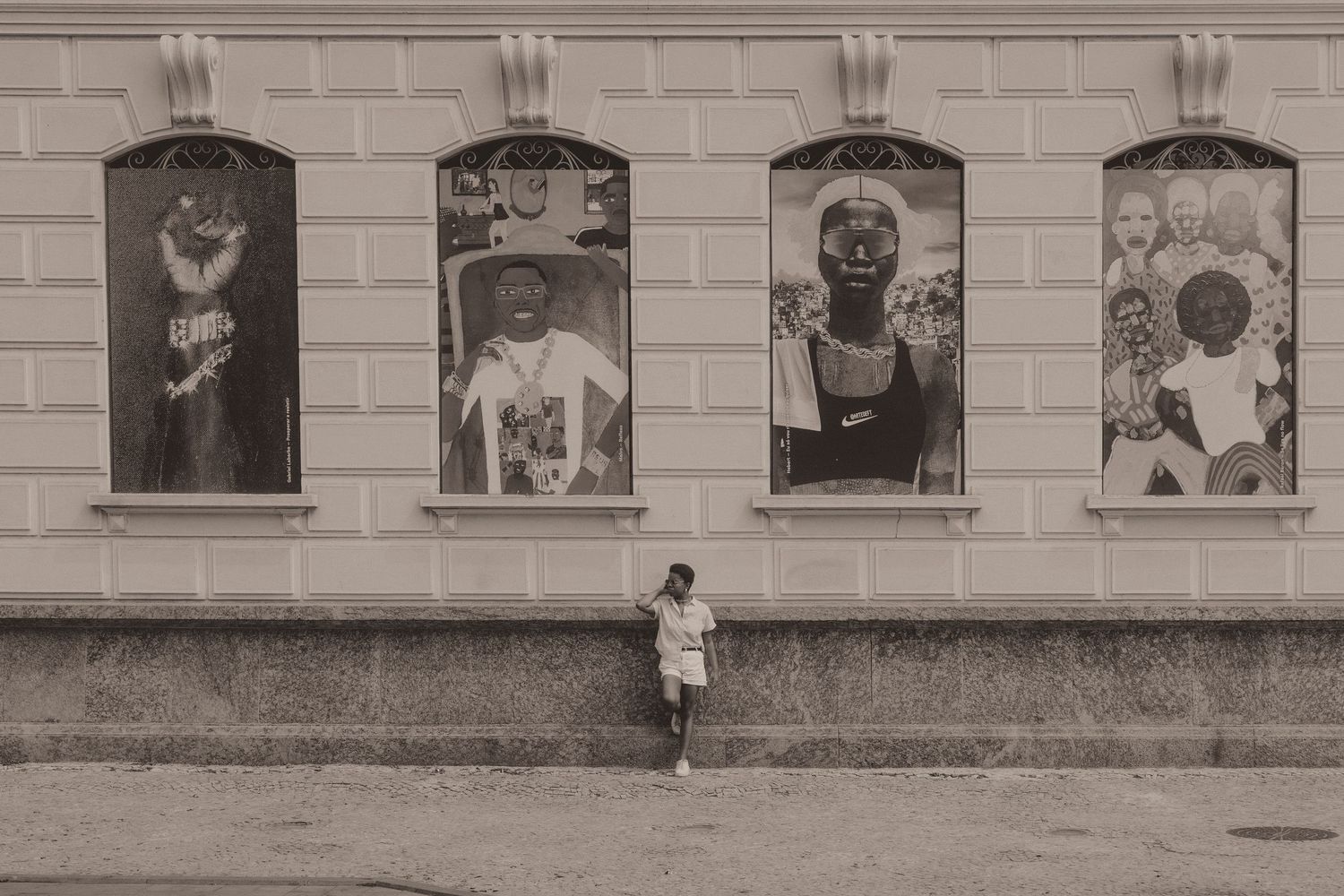 A series of sepia-toned vintage window portraits mounted on a building's exterior facade shows historical images.