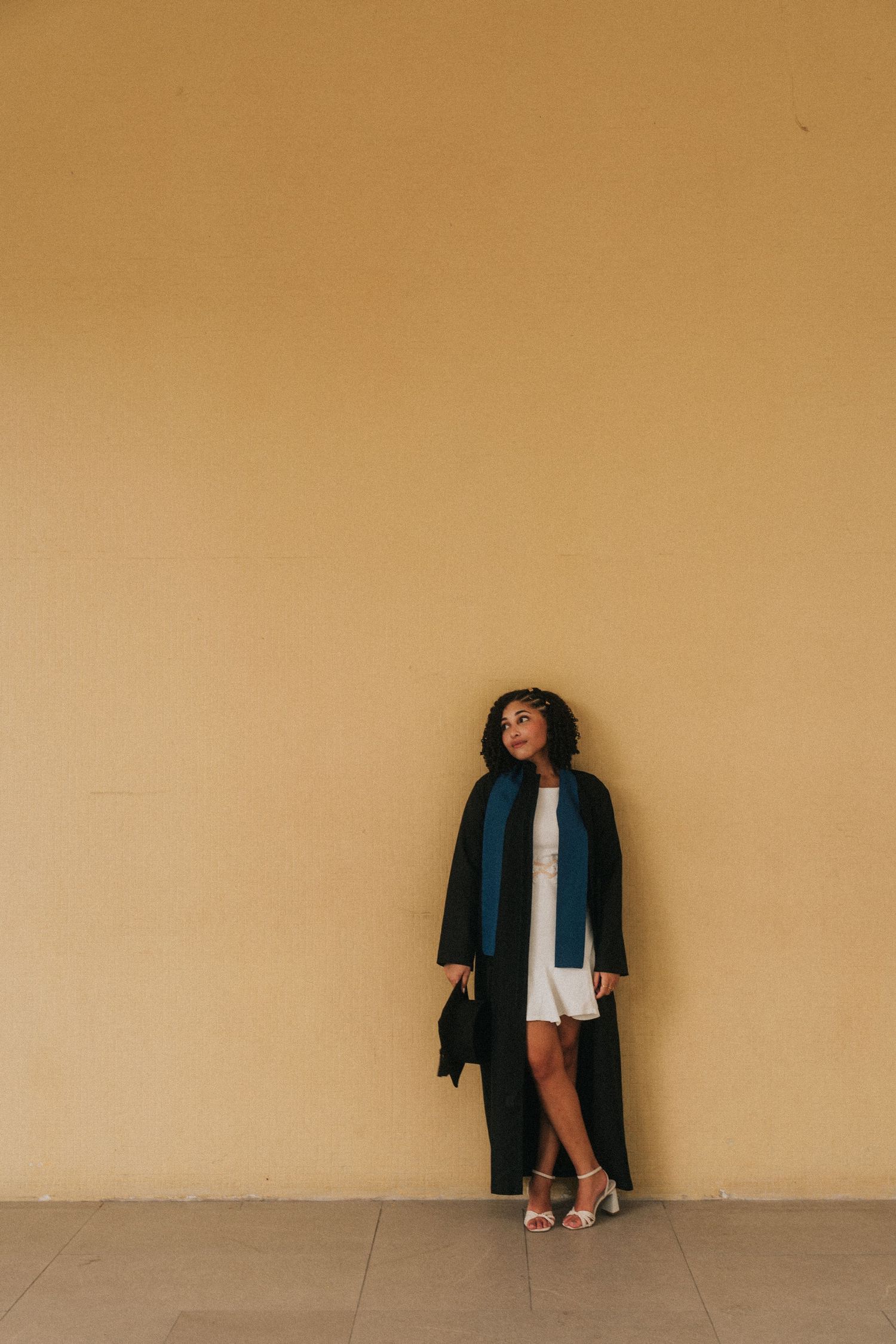 A minimalist fashion series showing a figure in a dark blazer against a beige wall photographed from different angles.