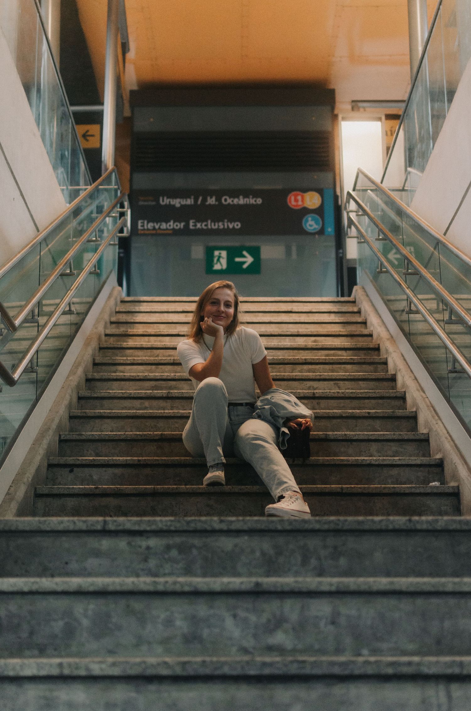 A melancholic sequence showing someone sitting alone on concrete subway station stairs in dim lighting.