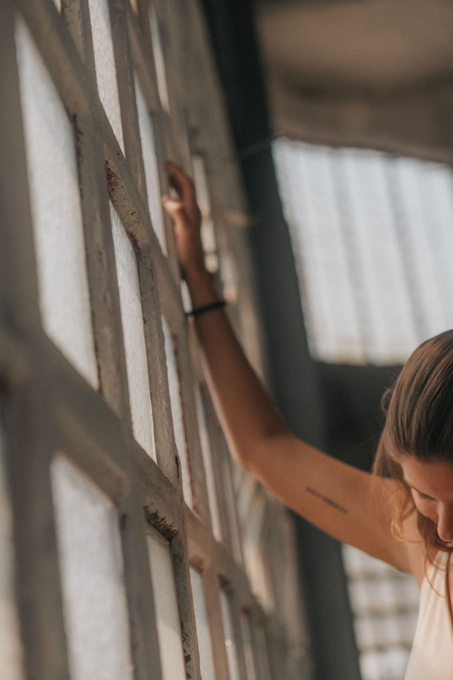 A person stretches upwards against a window with soft daylight streaming in, creating a serene silhouette.