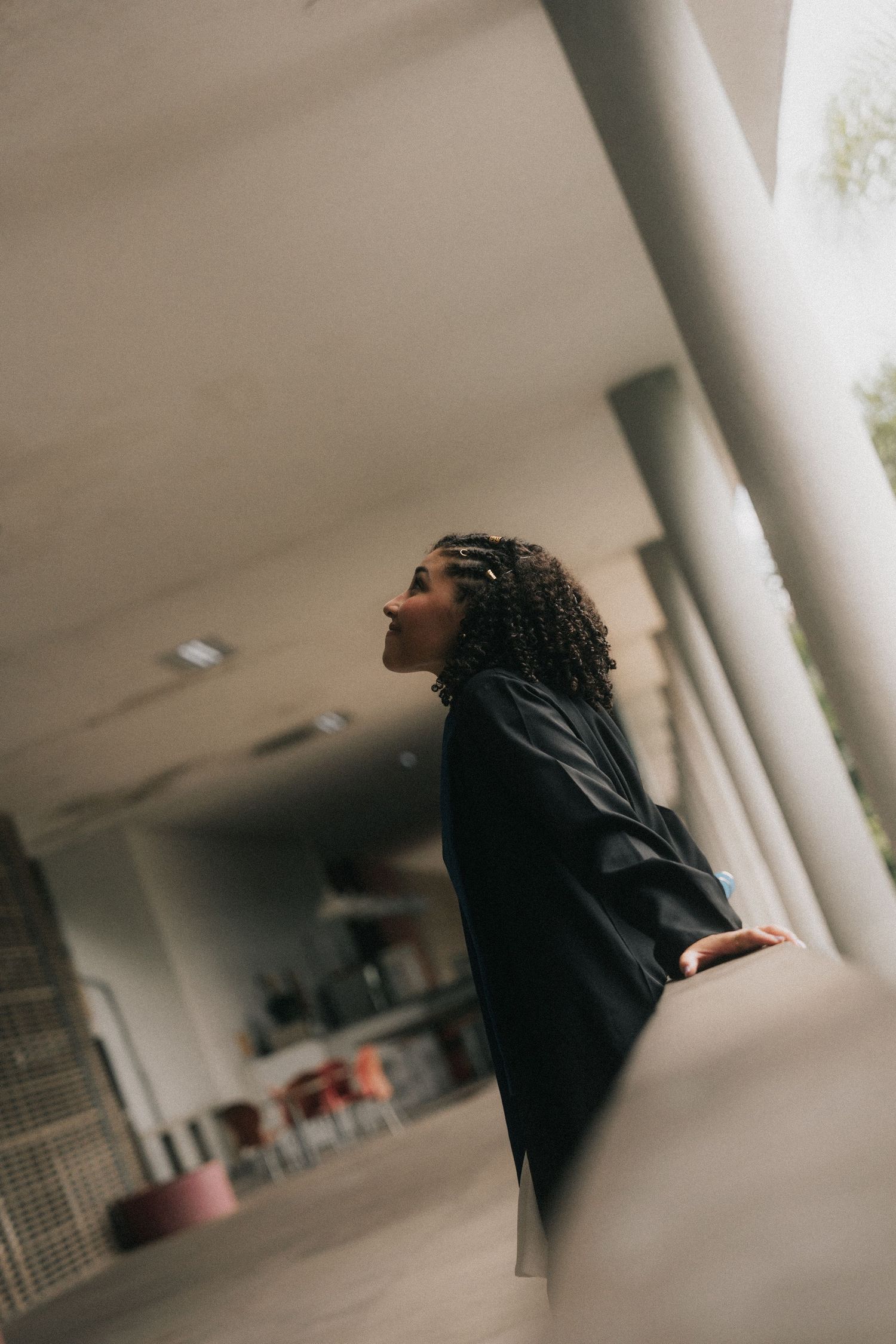 Person in black clothing moving dramatically through a corridor with white columns and blurred edges.