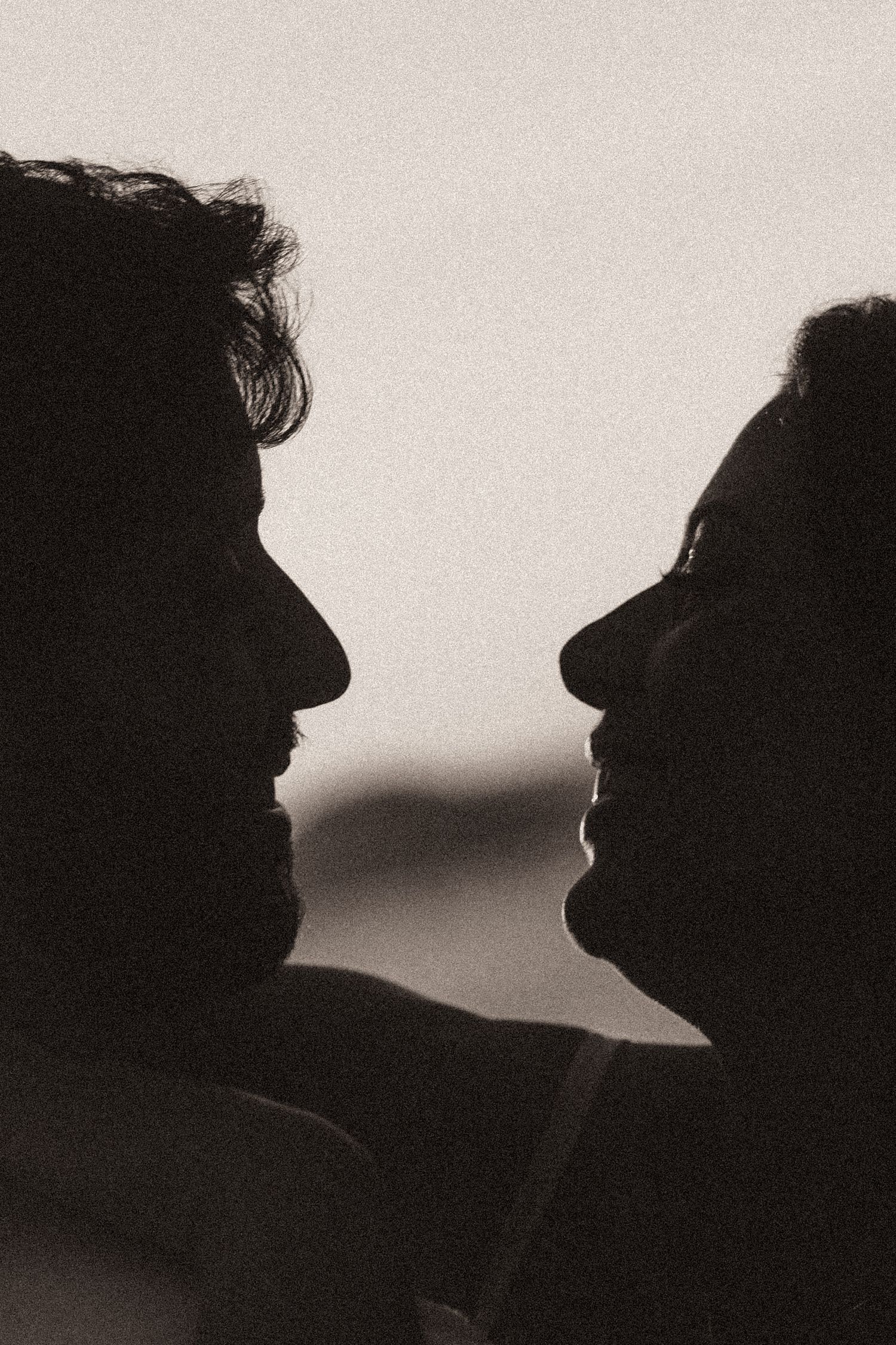 A series of black and white silhouettes of two people face to face, creating a repetitive visual pattern.