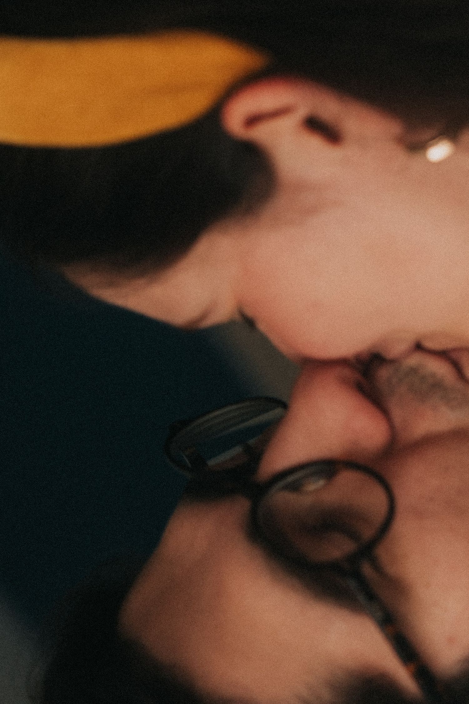 Dark and intimate close-up shot of two people sharing a tender romantic moment in dim lighting.