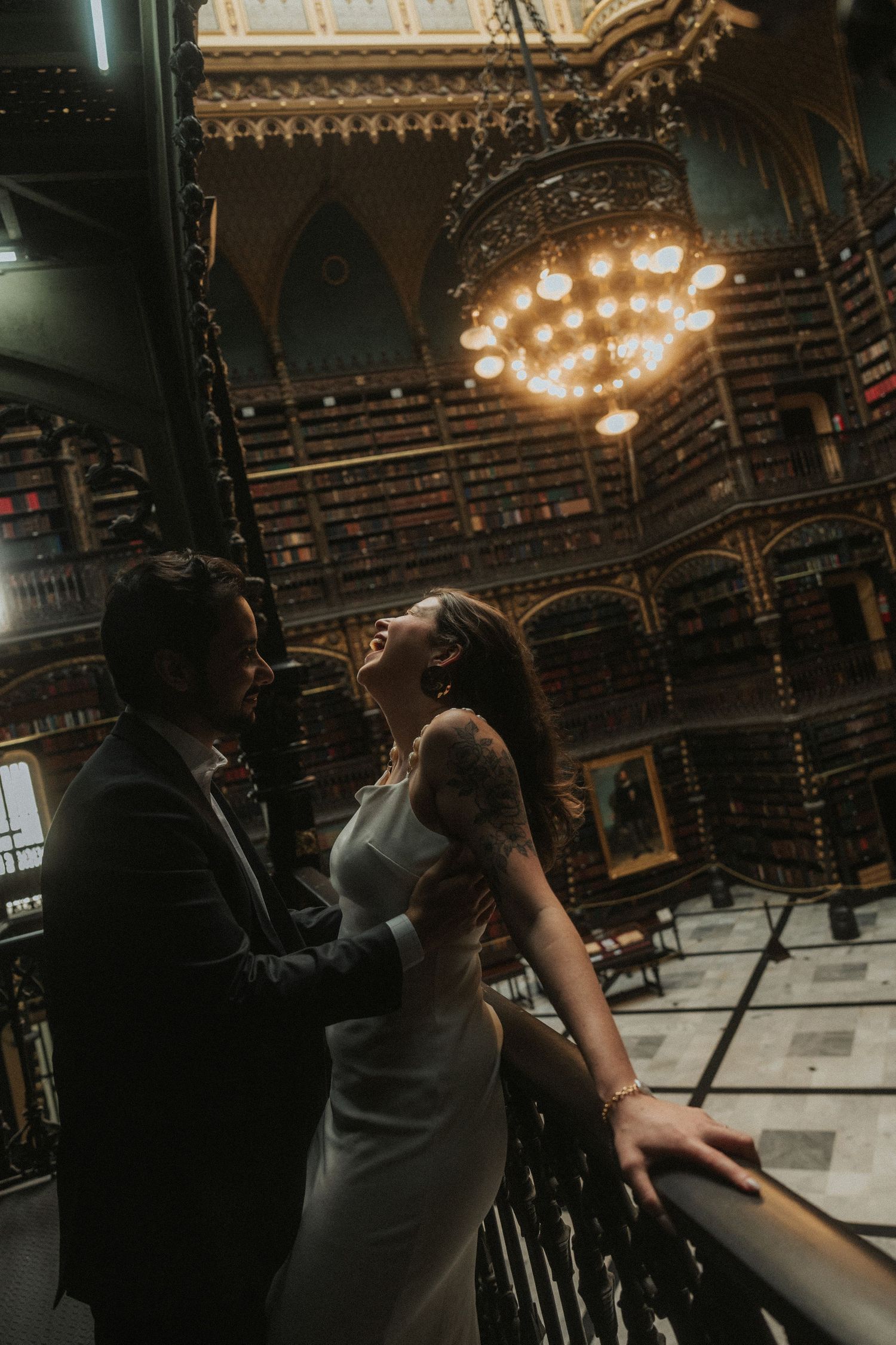 A couple dances together in an ornate ballroom with chandeliers and decorative architecture.