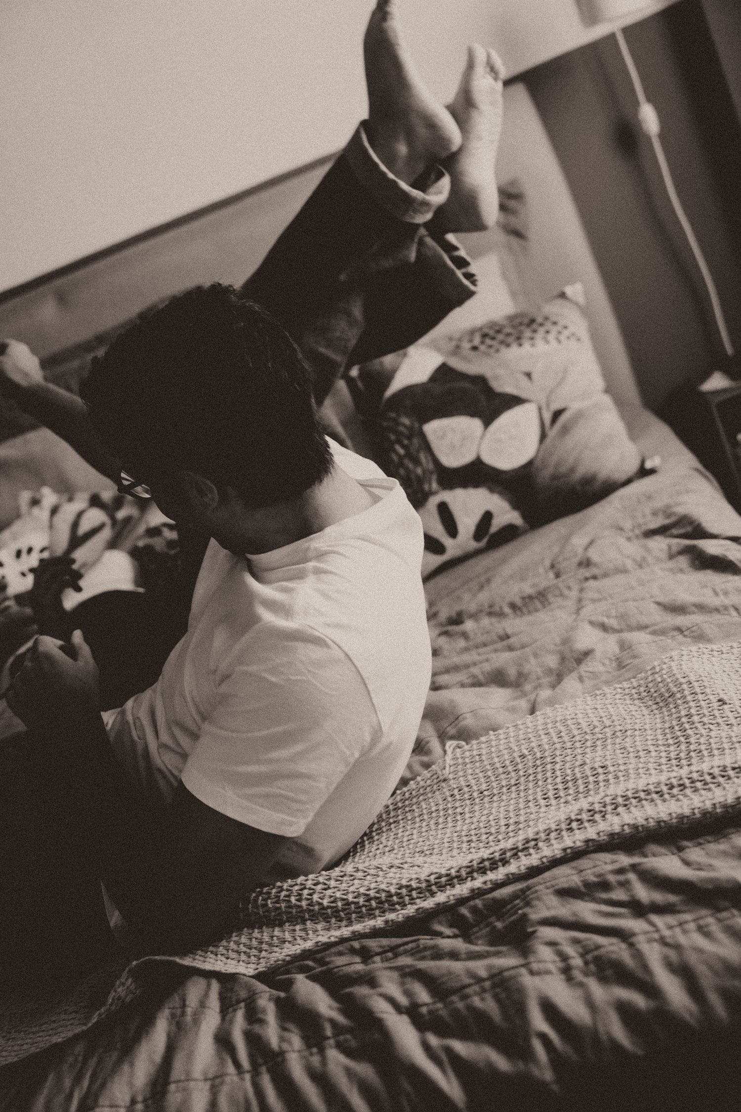 Black and white photo series showing a person in a white shirt sitting on a textured bedspread.