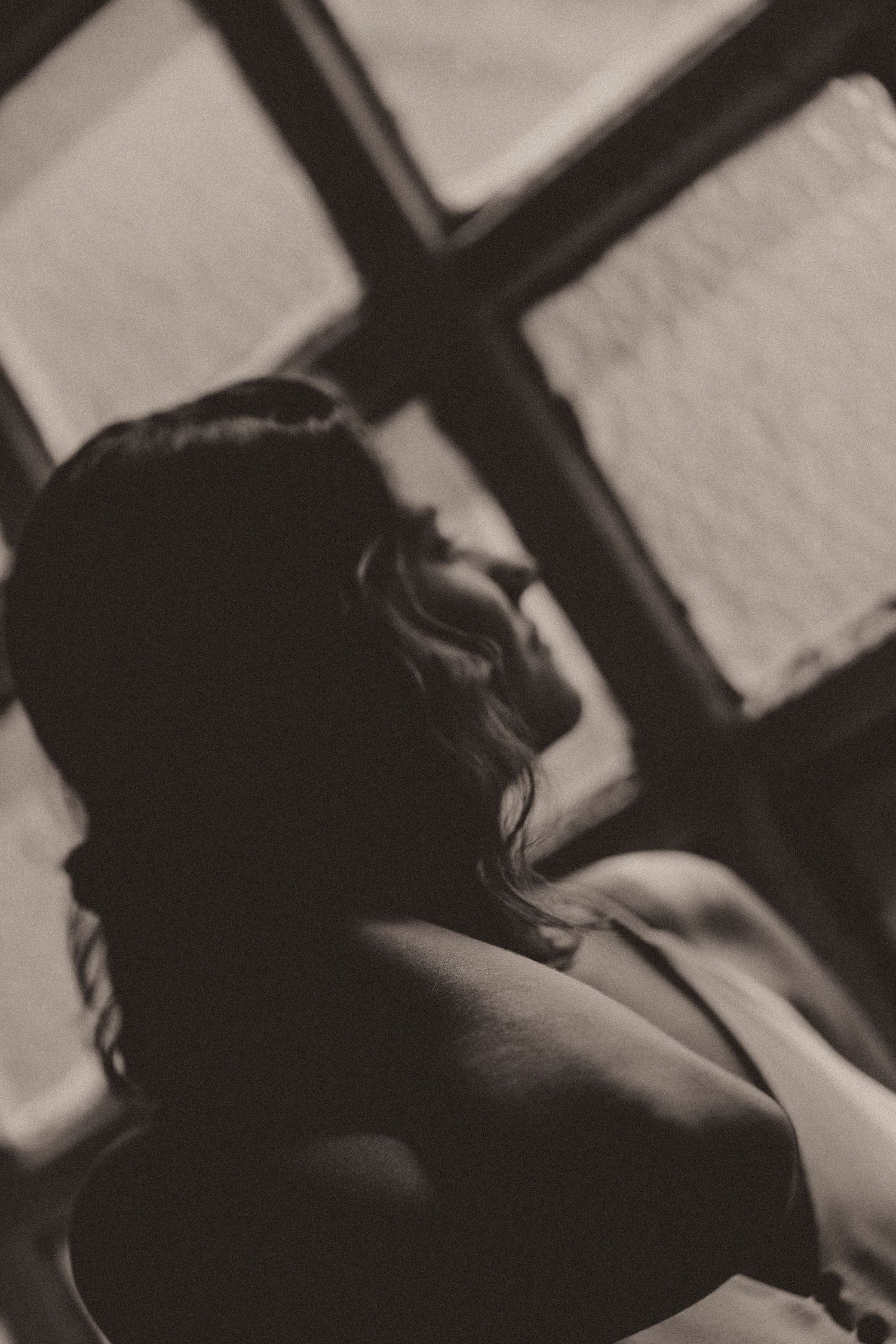 Woman lying down with hair covering face in vintage style black and white photograph, creating dramatic shadows.