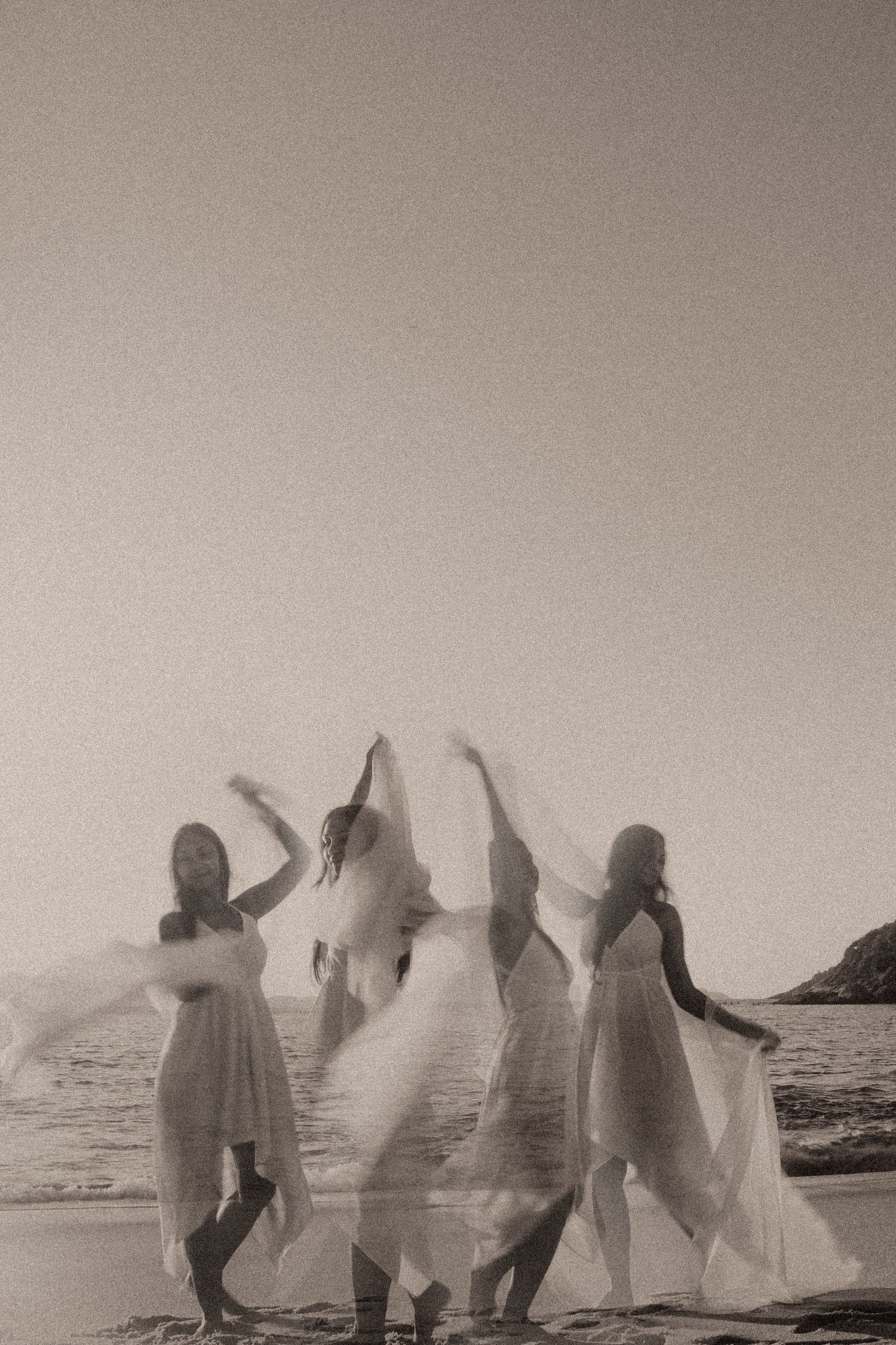 A vintage panoramic photo sequence shows ghostly figures in white sheets dancing on a beach at the ocean's edge.