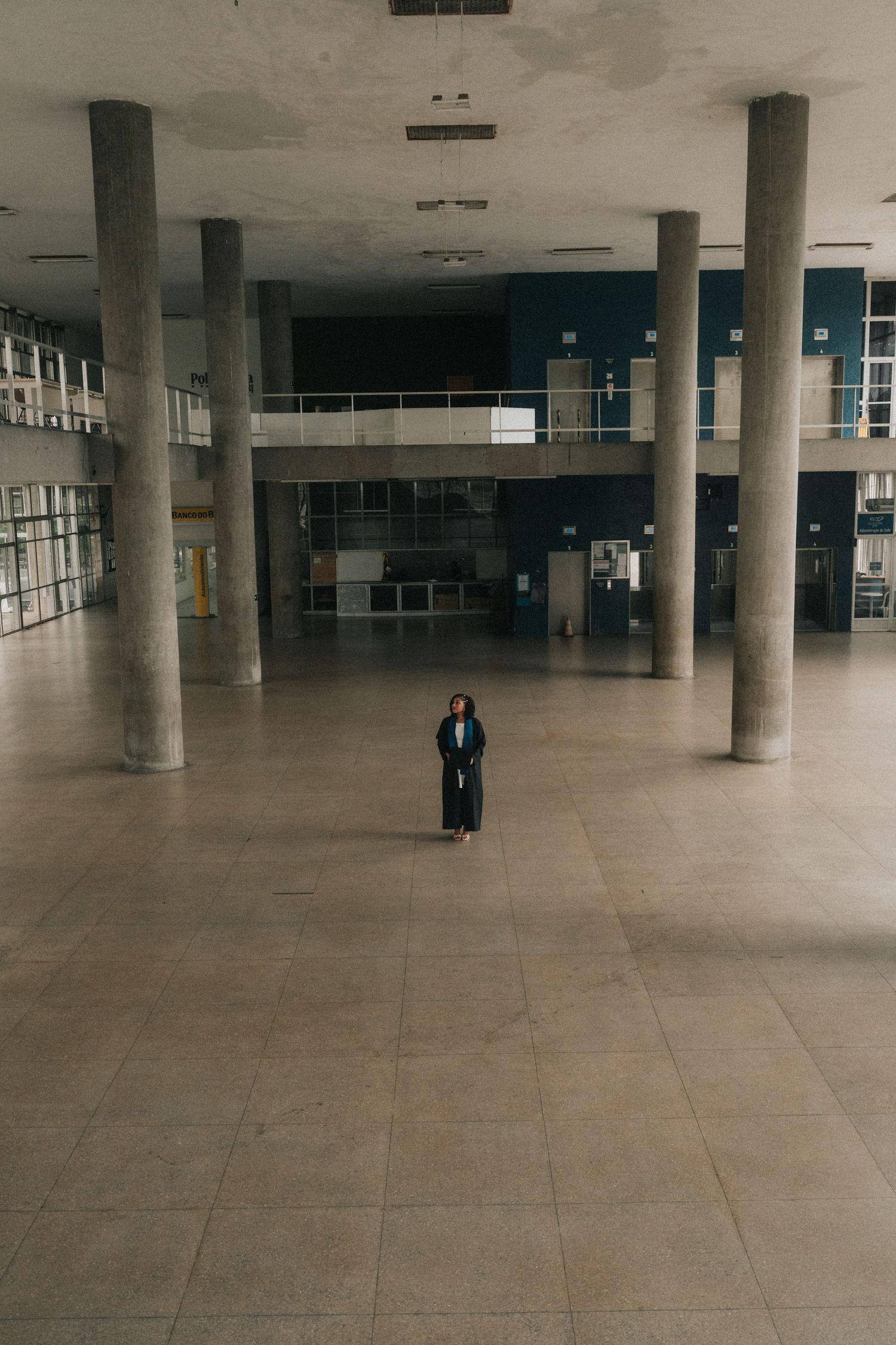 A vast empty indoor space with concrete pillars and tiled floors showing multiple angles of the same minimalist interior.