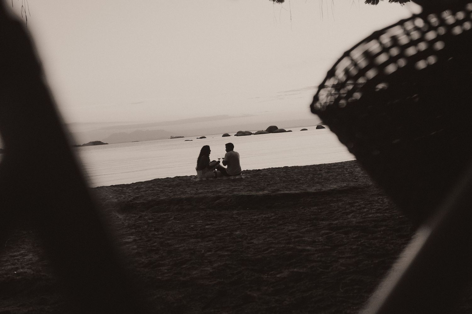 A series of black and white film photographs show various silhouettes against a moody beach landscape at sunset.