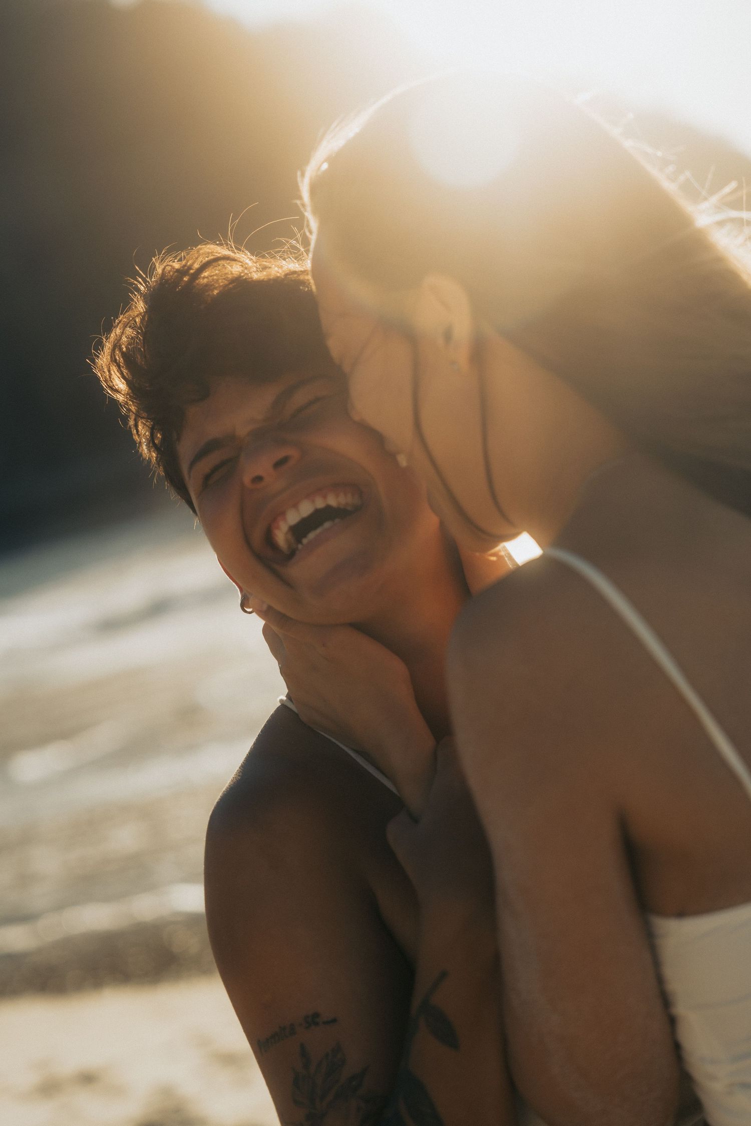 Beach portrait in golden sunlight showing joyful expressions and warm summer vibes.