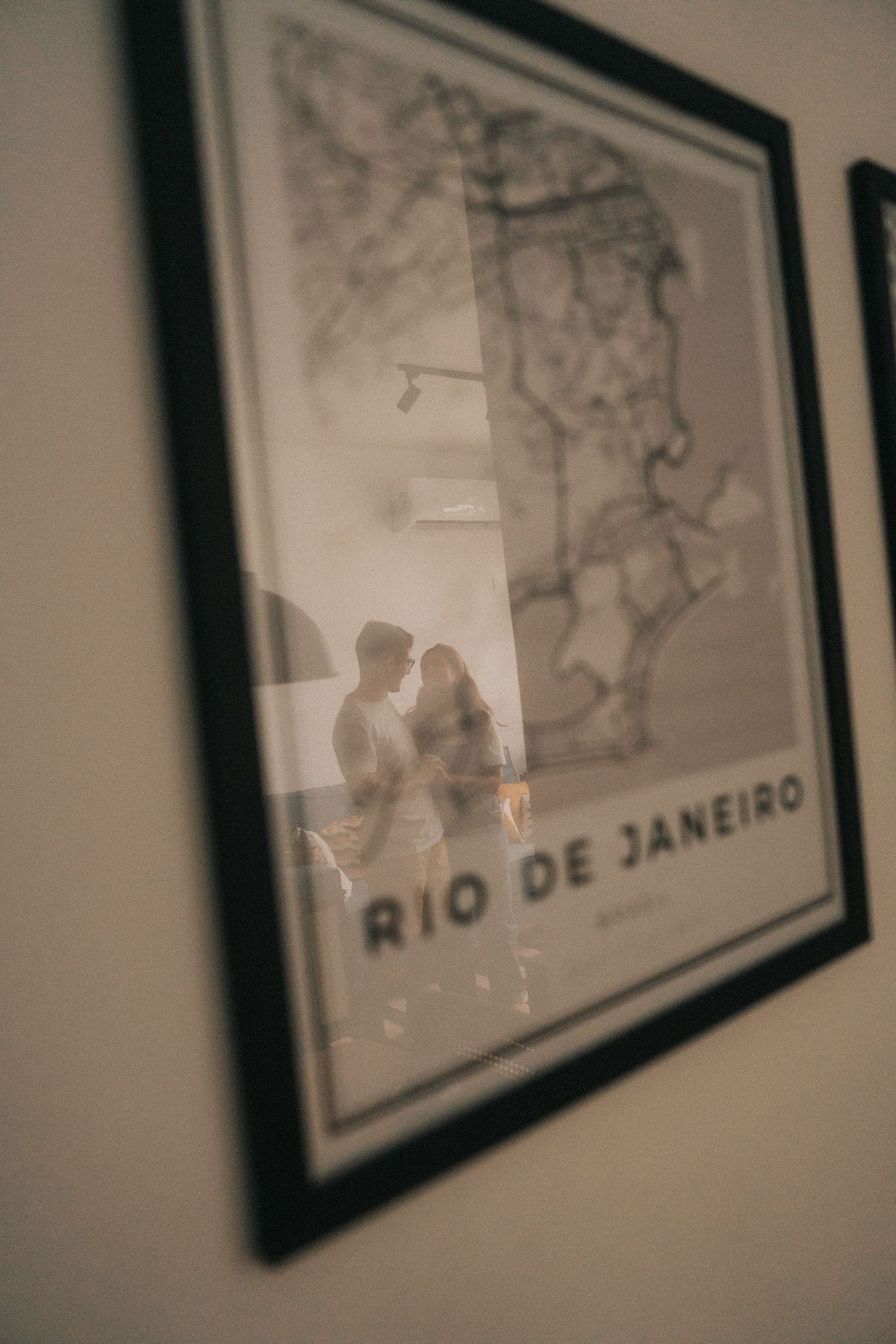 Blurred gallery wall with multiple framed black and white maps or artwork in dark lit room.