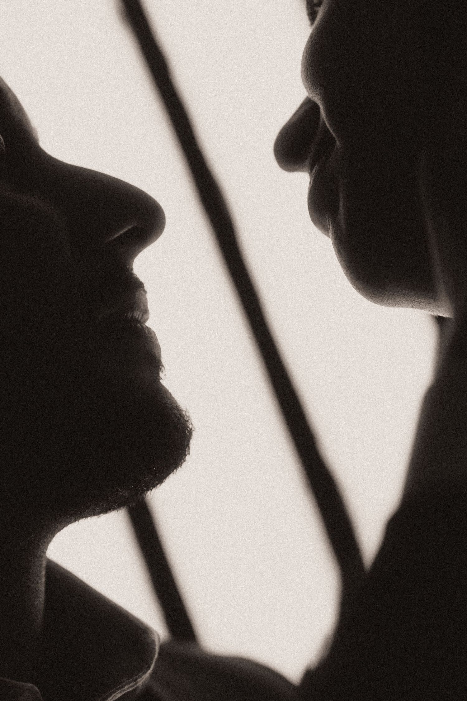 Artistic black and white silhouette profile portraits showing dramatic side views against diagonal lines.