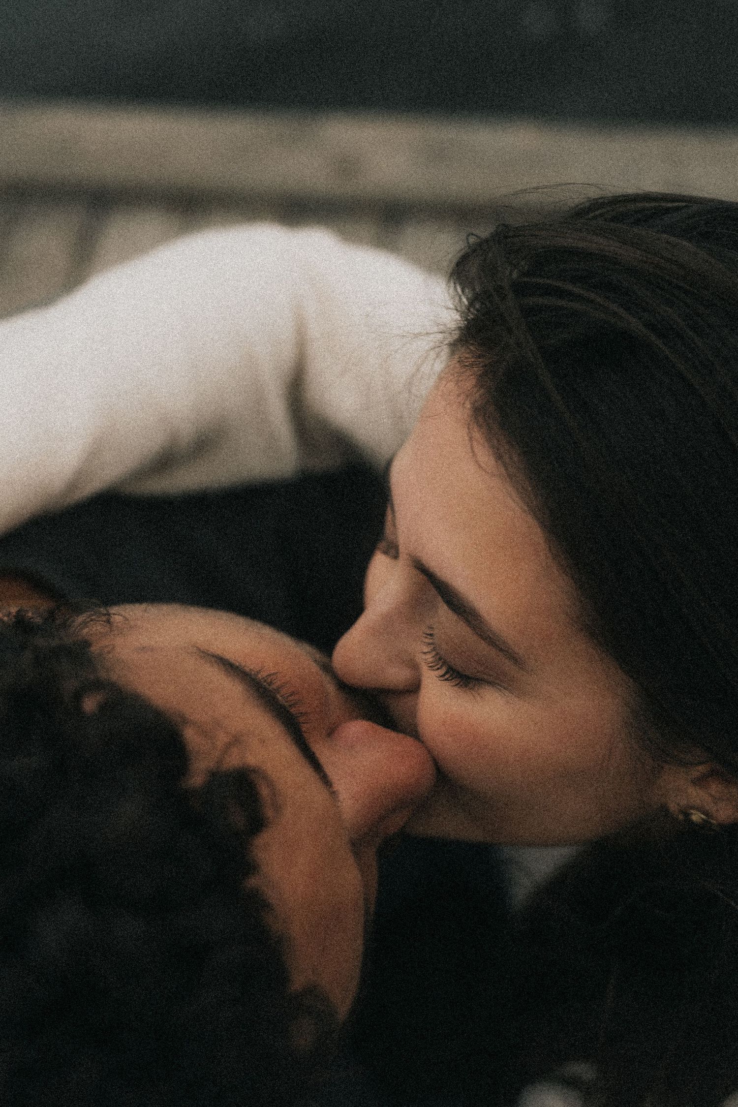 A loving couple shares an intimate kiss in a moody, dark romantic setting.