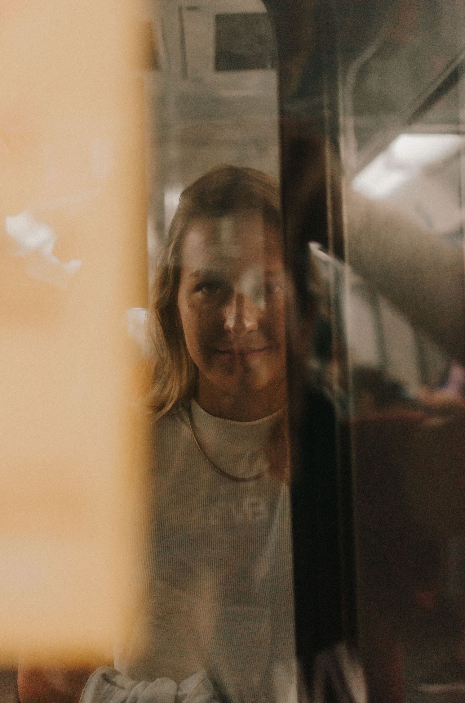 Artistic multiple exposure portrait of someone's reflection seen through glass panels creating a moody atmospheric effect.