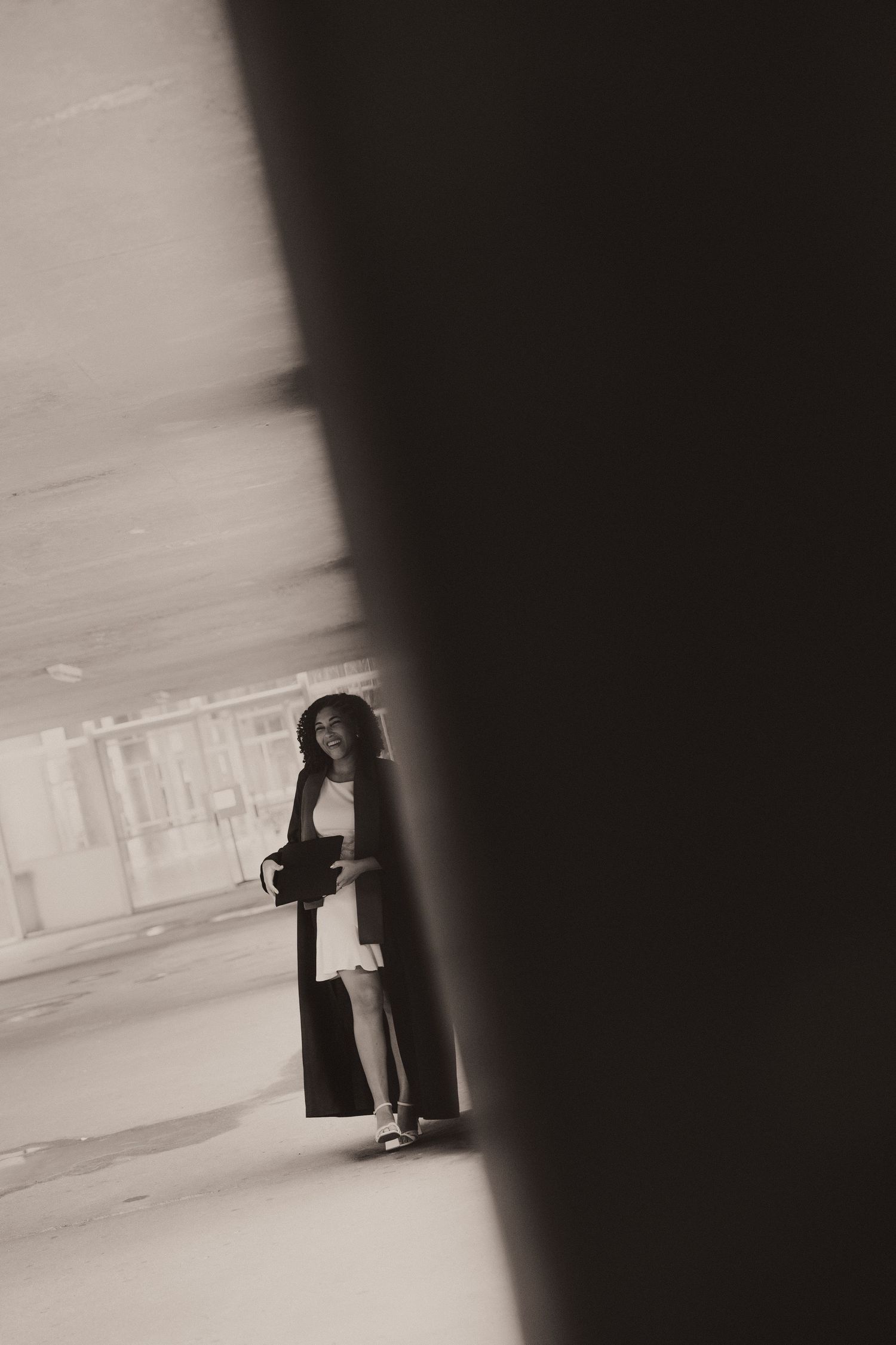 Dramatic black and white artistic photo of someone standing in a minimalist corridor with strong shadows.