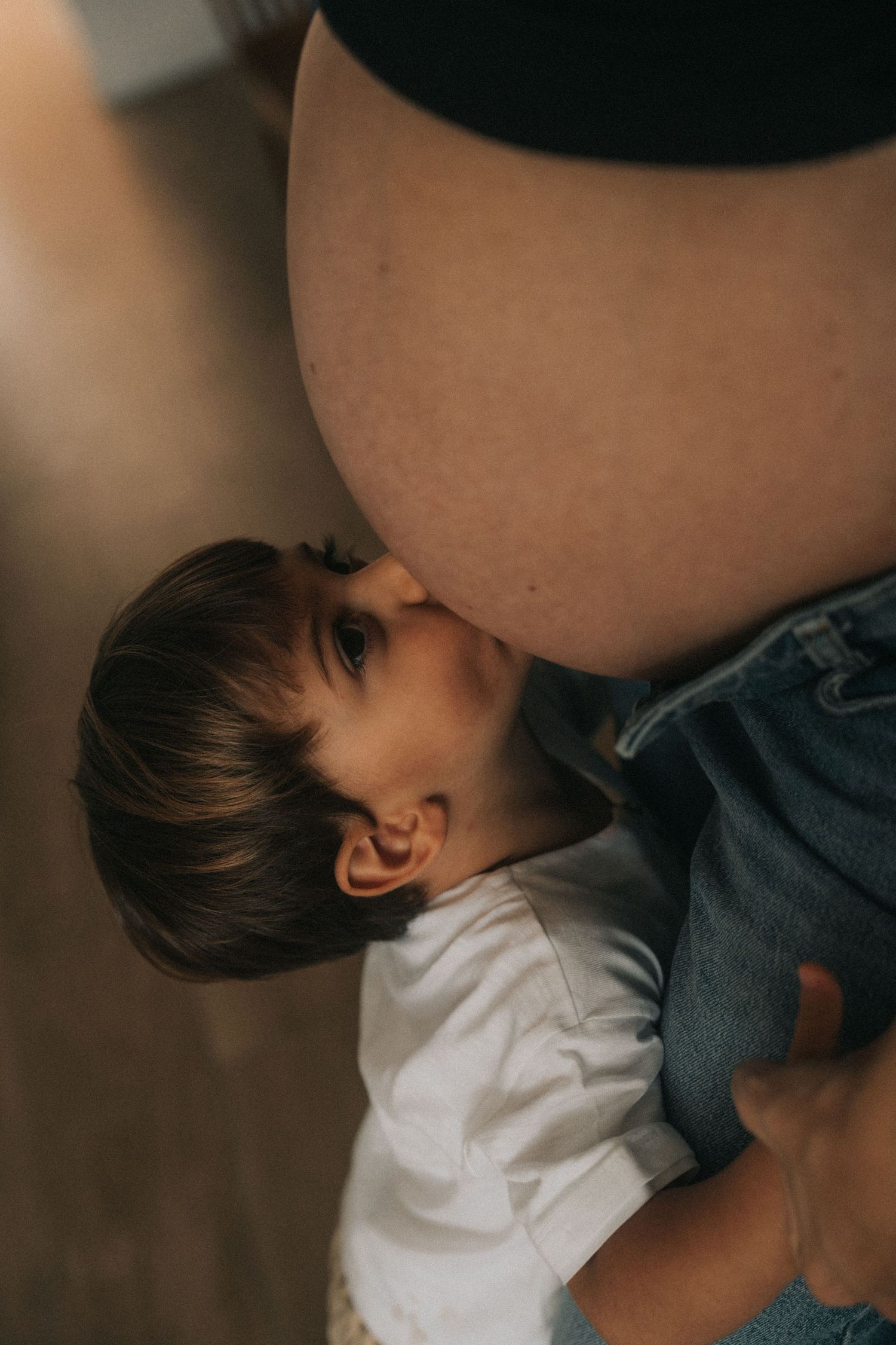 A tender moment between a small child and a pregnant belly.