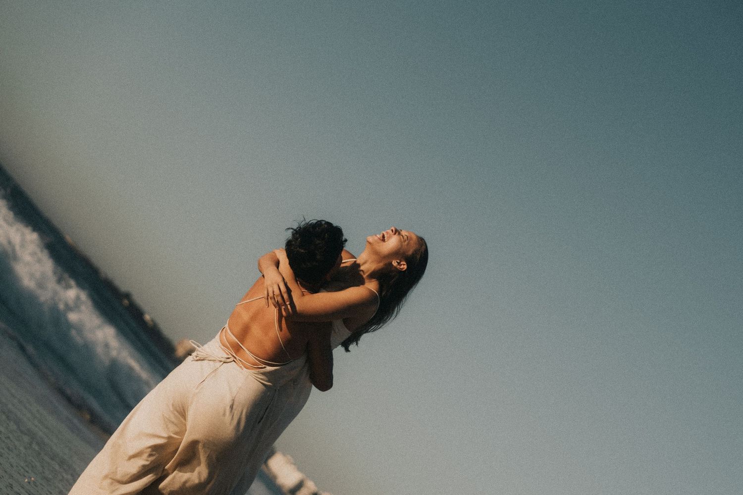 Person standing on scenic coastal cliffs at sunset enjoying dramatic ocean views while looking upward.