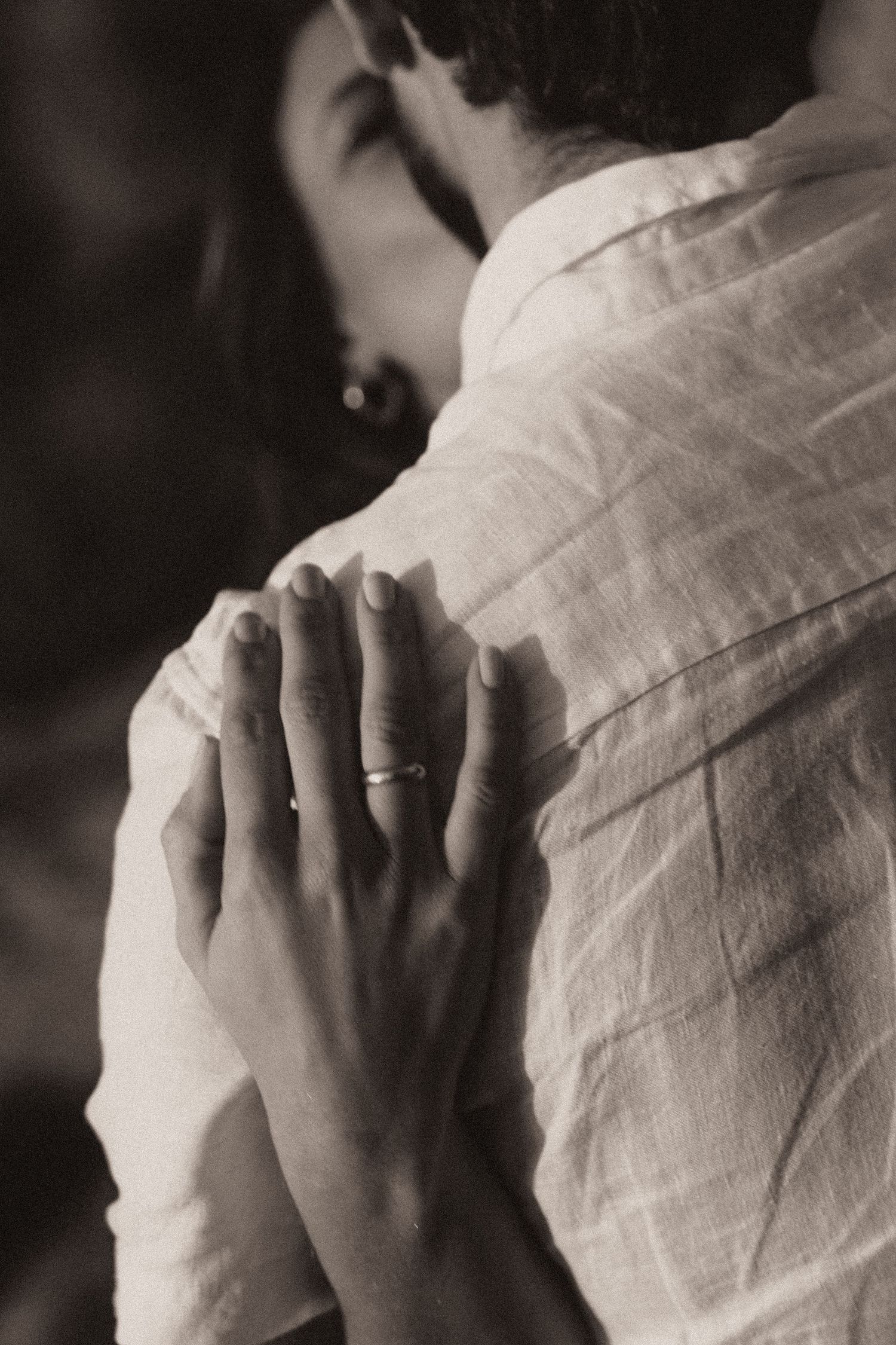 Black and white photo of hands holding a pillow or soft fabric with gentle folds and delicate shadows.