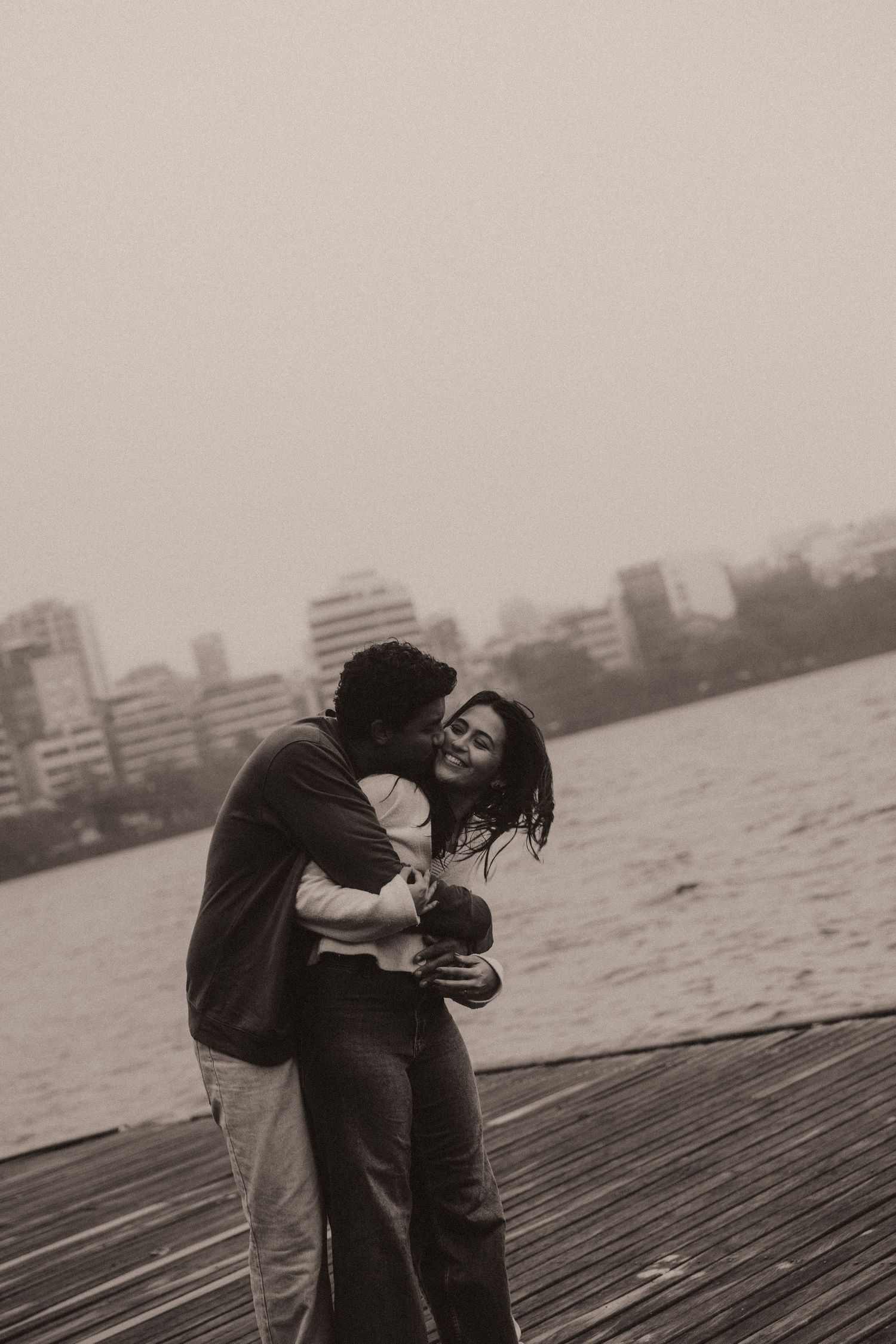 A romantic black and white photo sequence shows two people embracing near water with city buildings in the background.