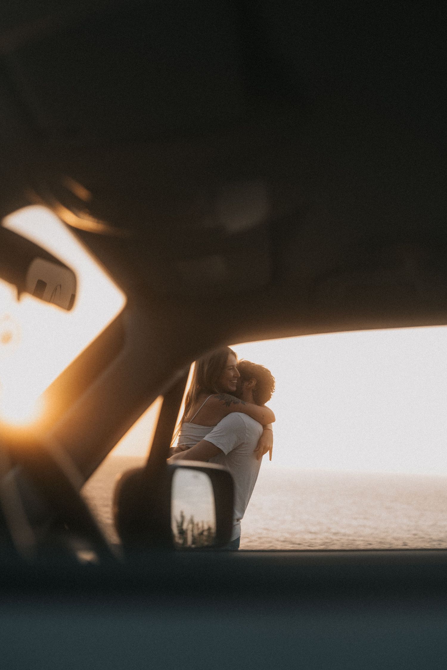 A dreamy sunset view through a car window showing a figure leaning out.