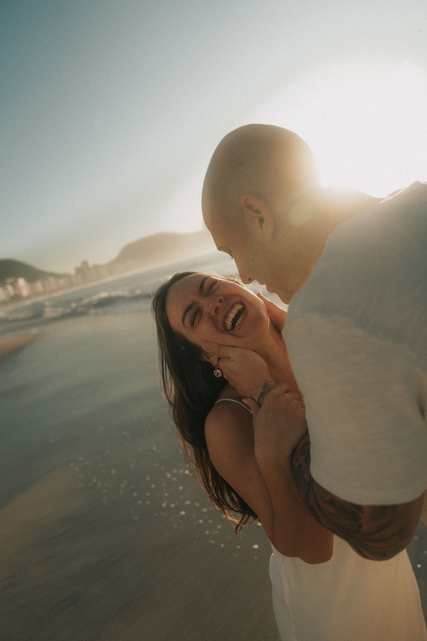 A couple shares an intimate moment at sunset on the beach, silhouetted against the golden sky.