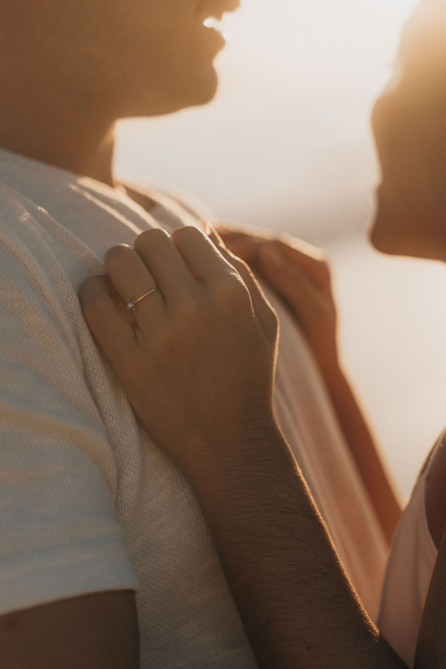 A silhouette of a couple embracing against warm sunlit background creates a romantic atmospheric mood.