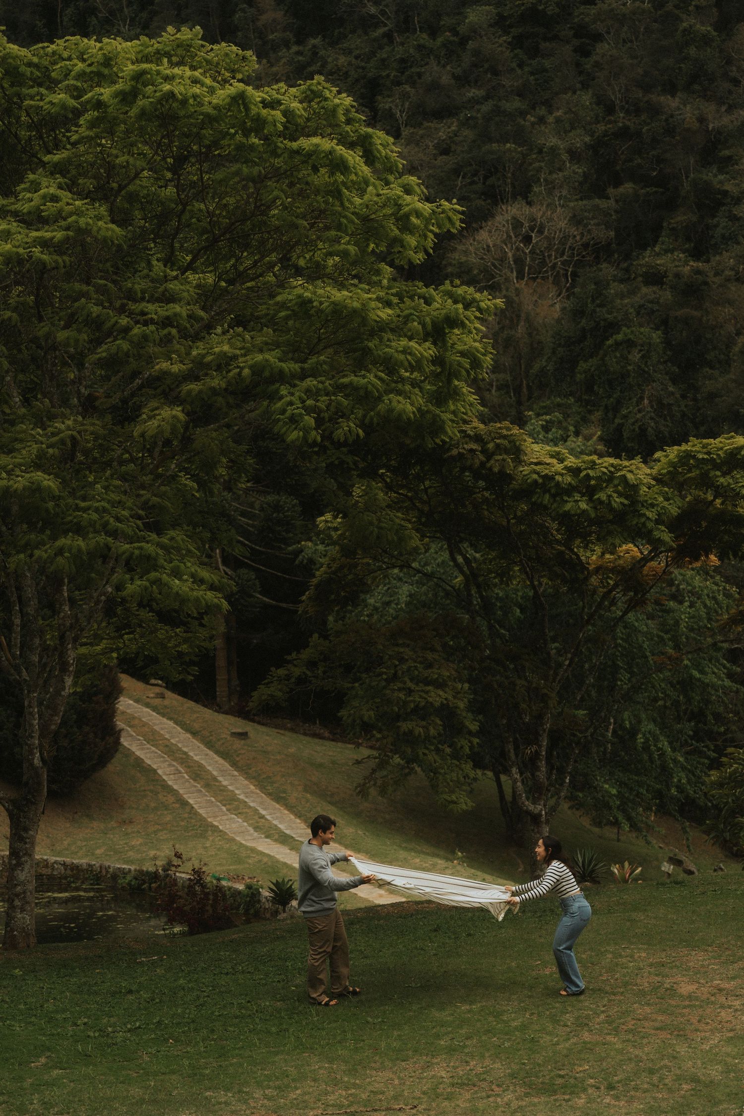 Children playing on a homemade slip-n-slide on a grassy hill during a summer day.