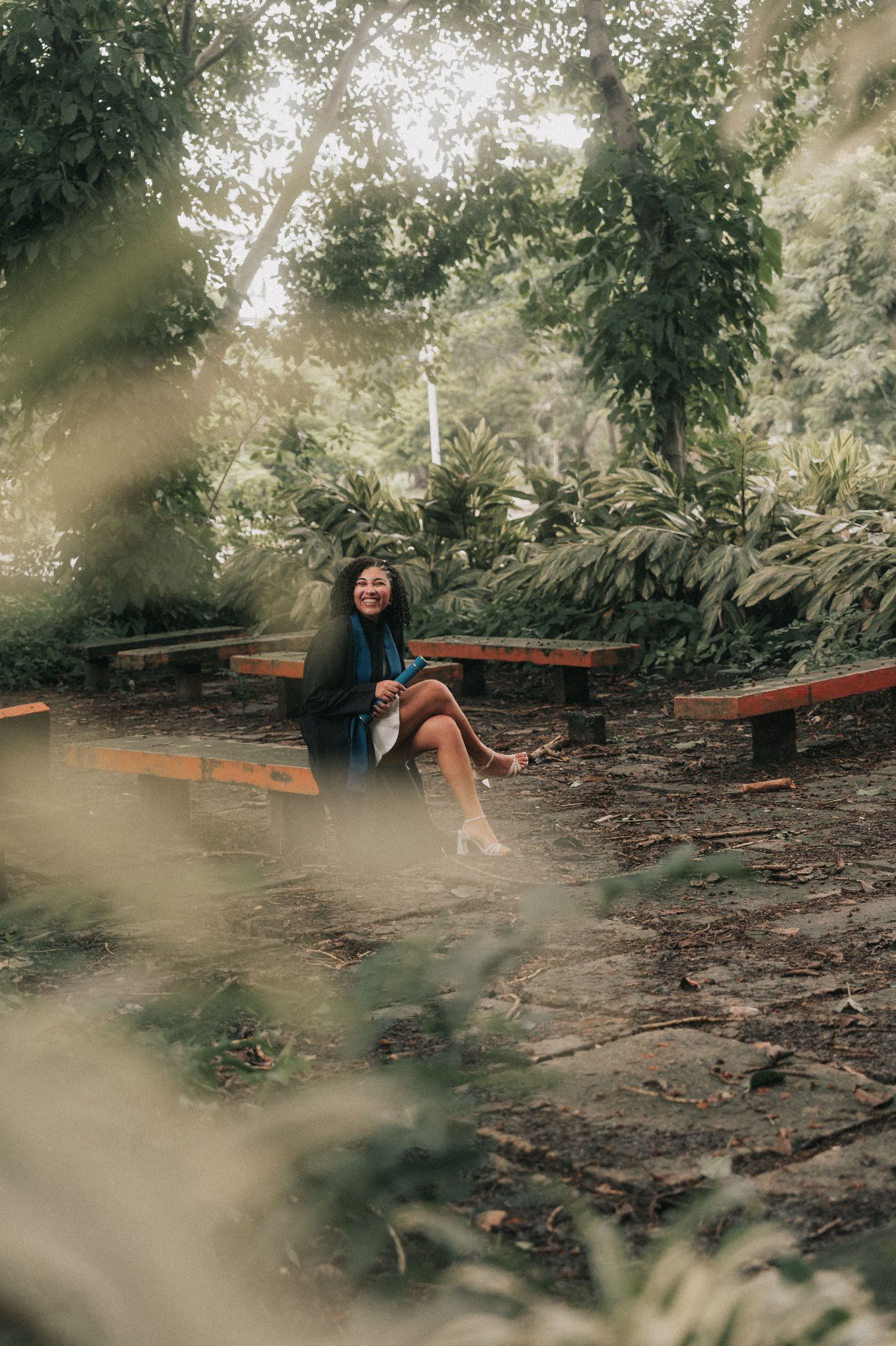 A person in casual attire lies in a serene wooded area with scattered logs and natural debris on the ground.