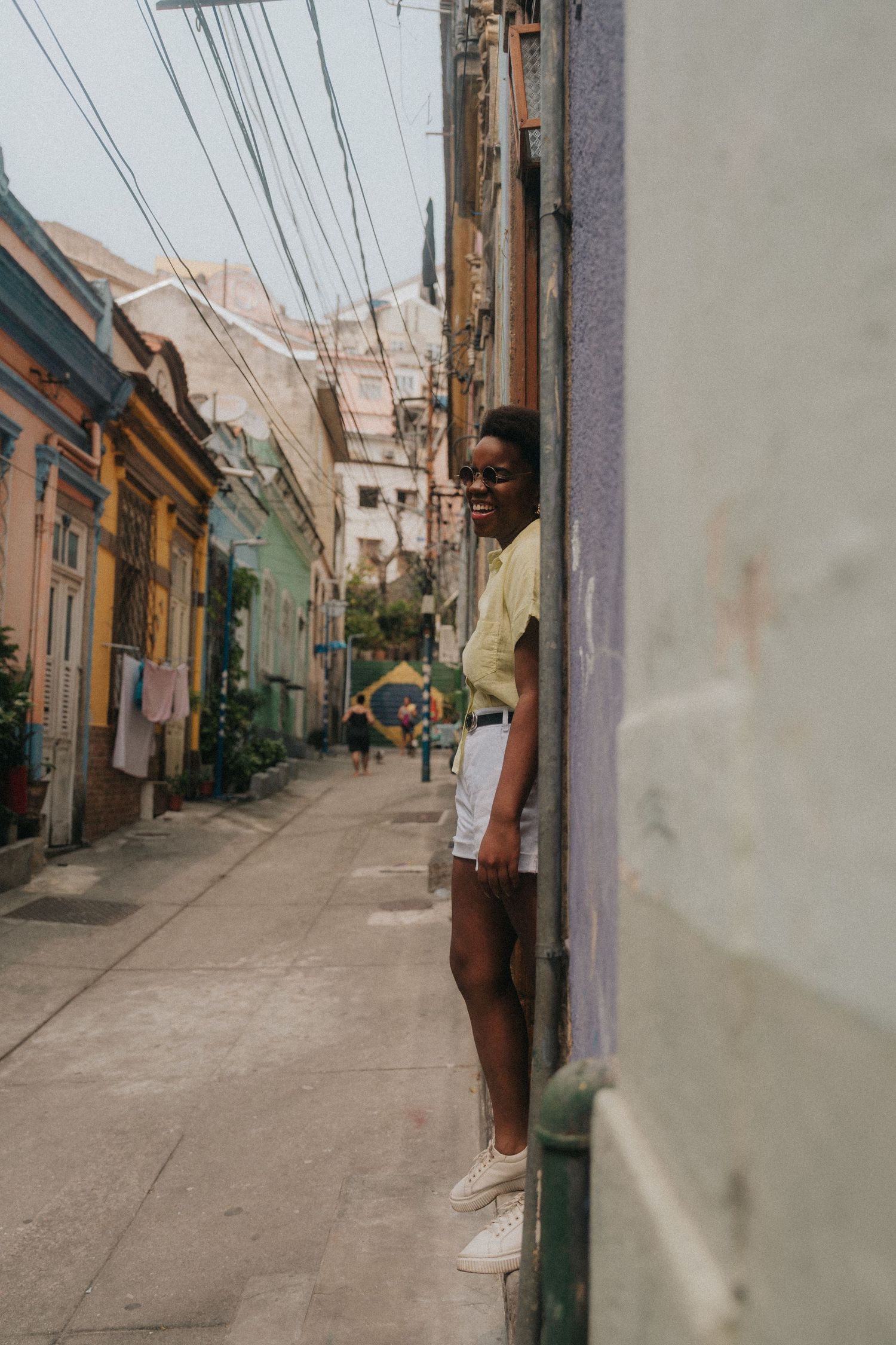 Narrow cobblestone street lined with colorful buildings in a Latin American neighborhood leads into distant mountains.