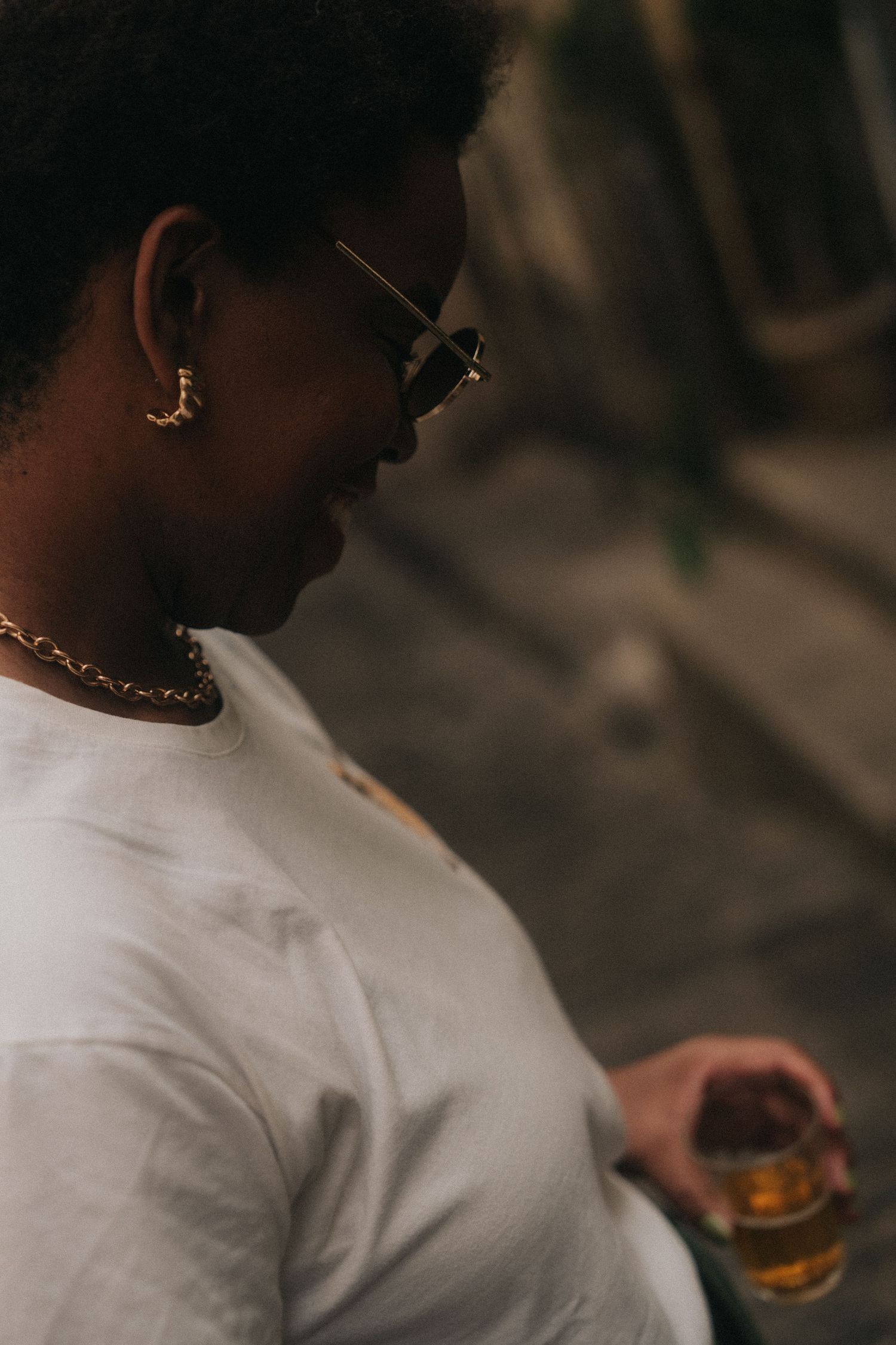Side profile of someone wearing a white shirt delicately sipping a beverage.