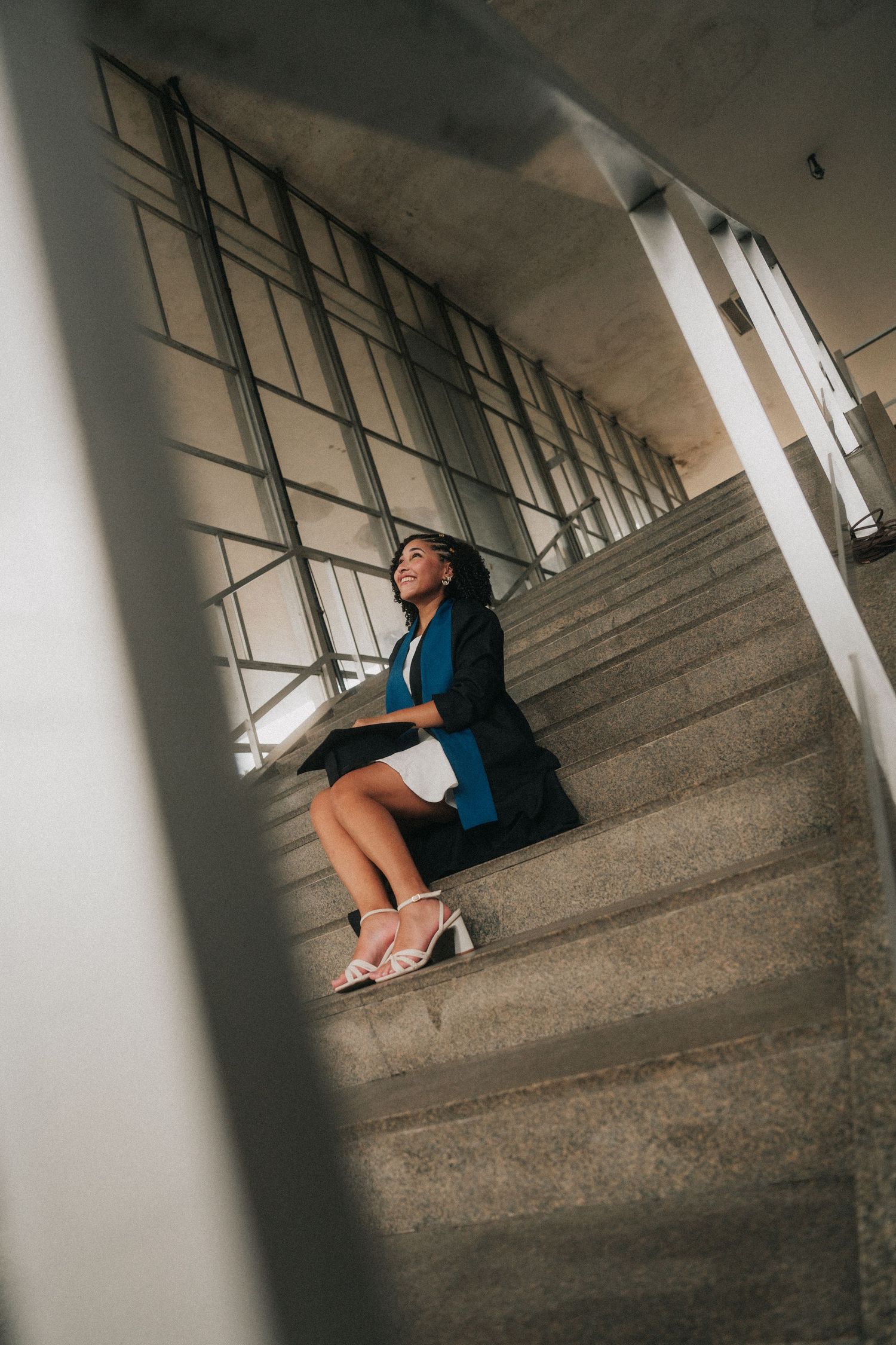 A woman sits in a slanted architectural space with dramatic shadows and lines created by windows and walls.