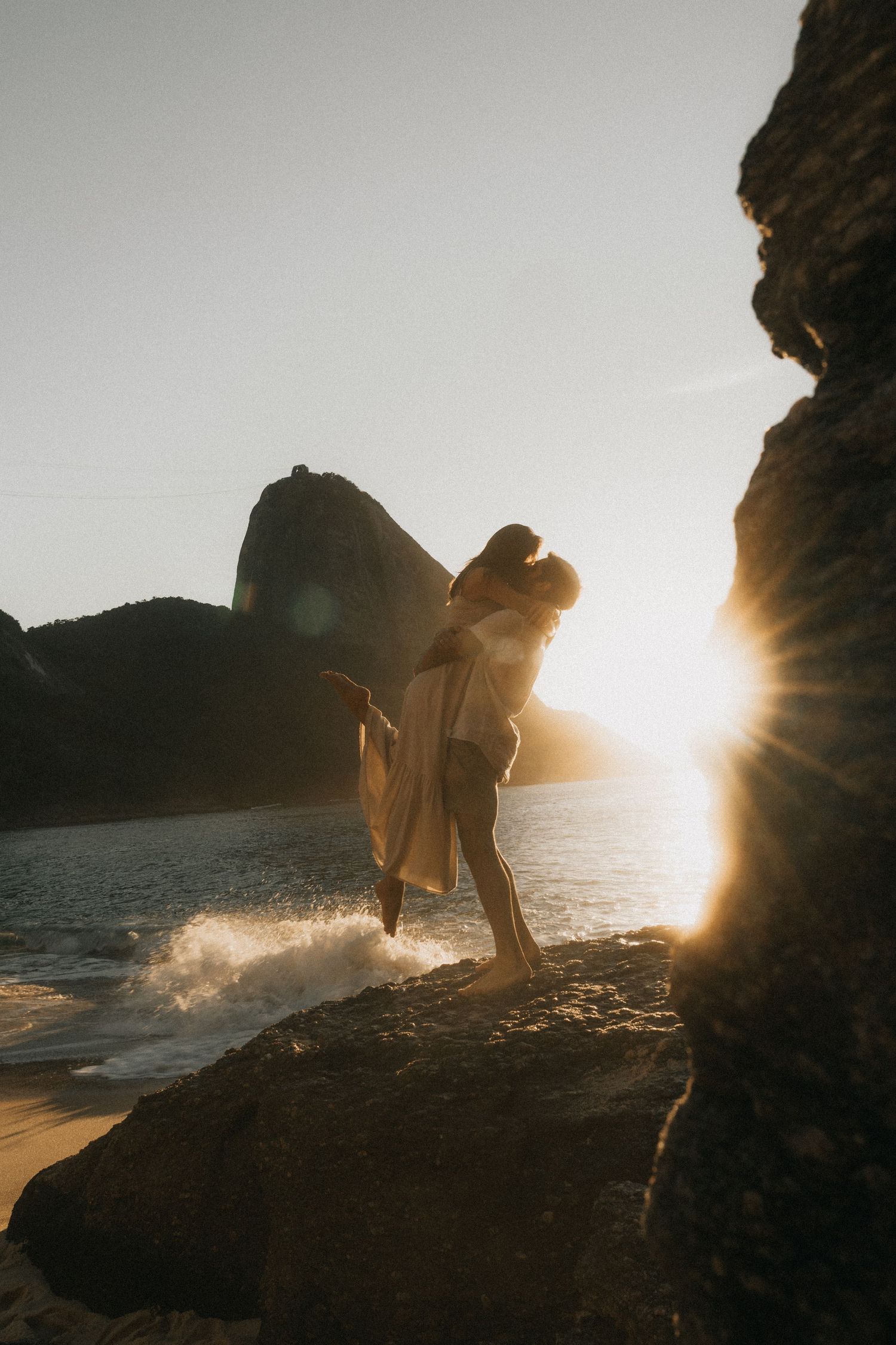 A silhouetted figure walks along rocky coastal cliffs at sunset as waves crash against the shore in a dramatic sequence.