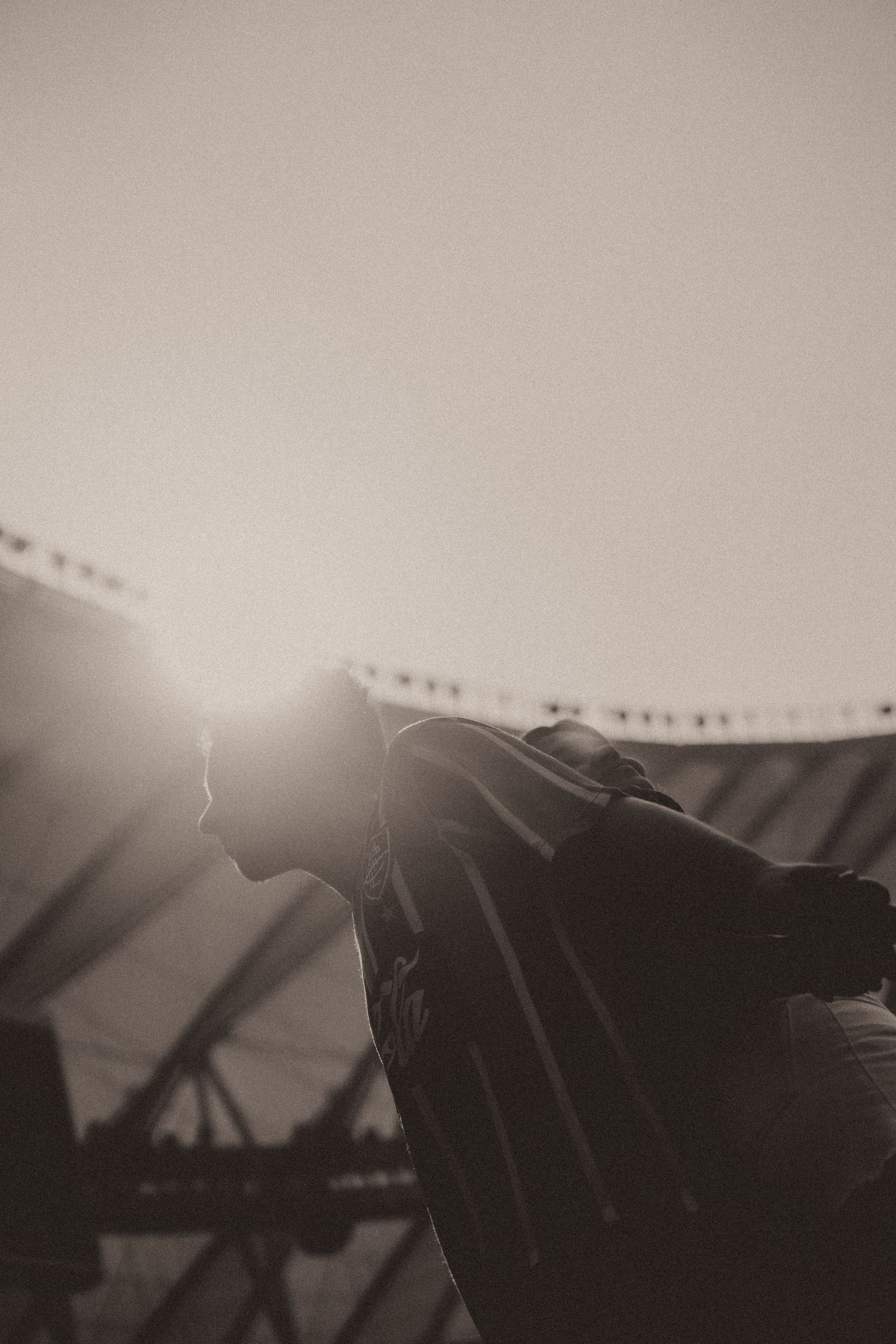Black and white silhouettes of carnival rides and string lights against a moody sky at dusk.