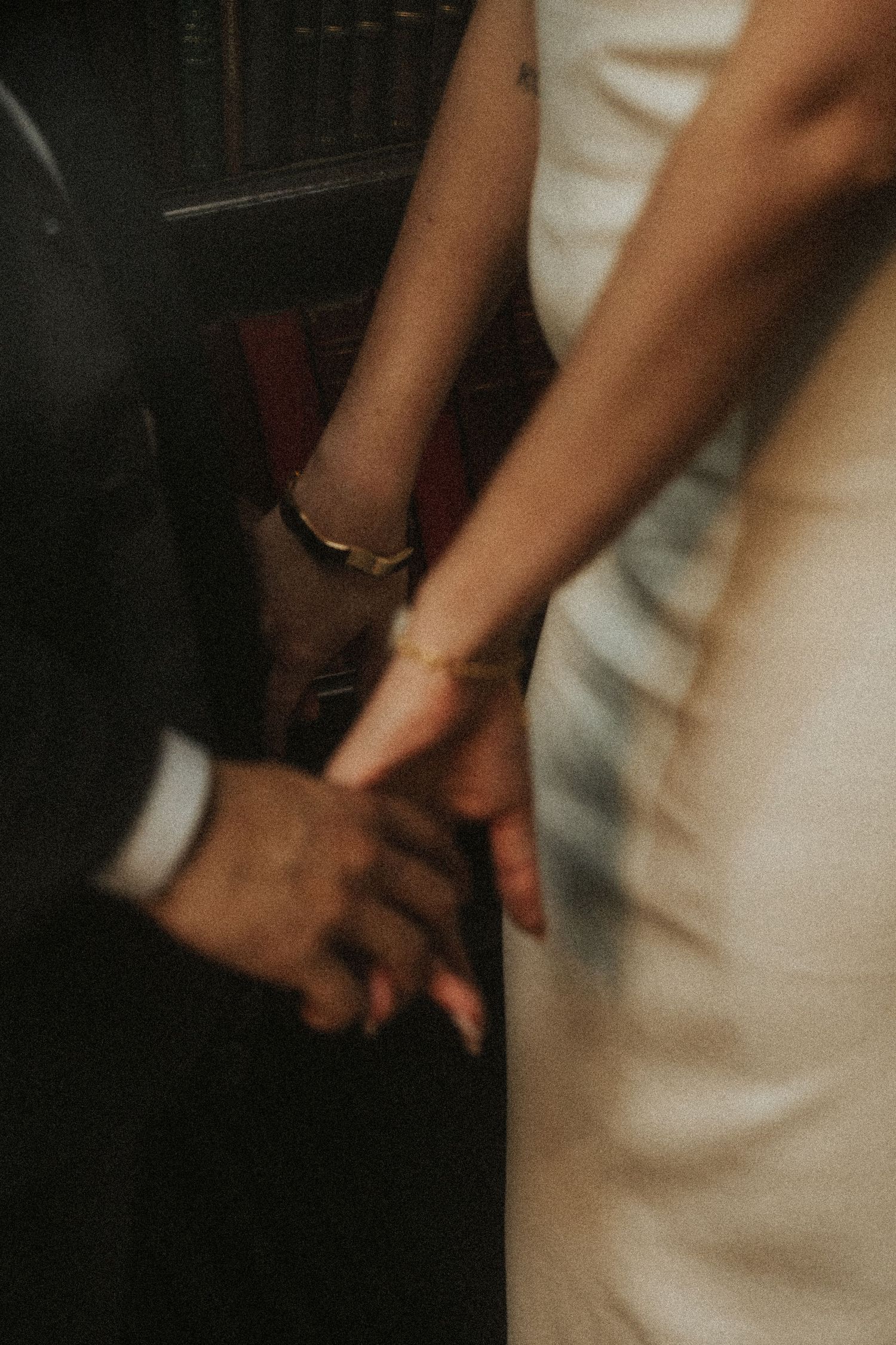 Close-up view of hands holding a delicate white wedding dress in soft, natural lighting.