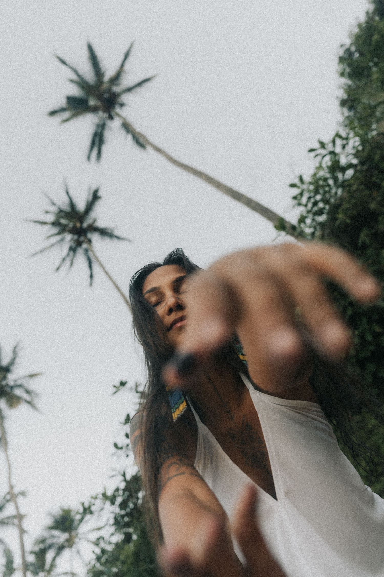 Low angle portrait against palm trees with dreamy perspective capturing tropical summer vibes.