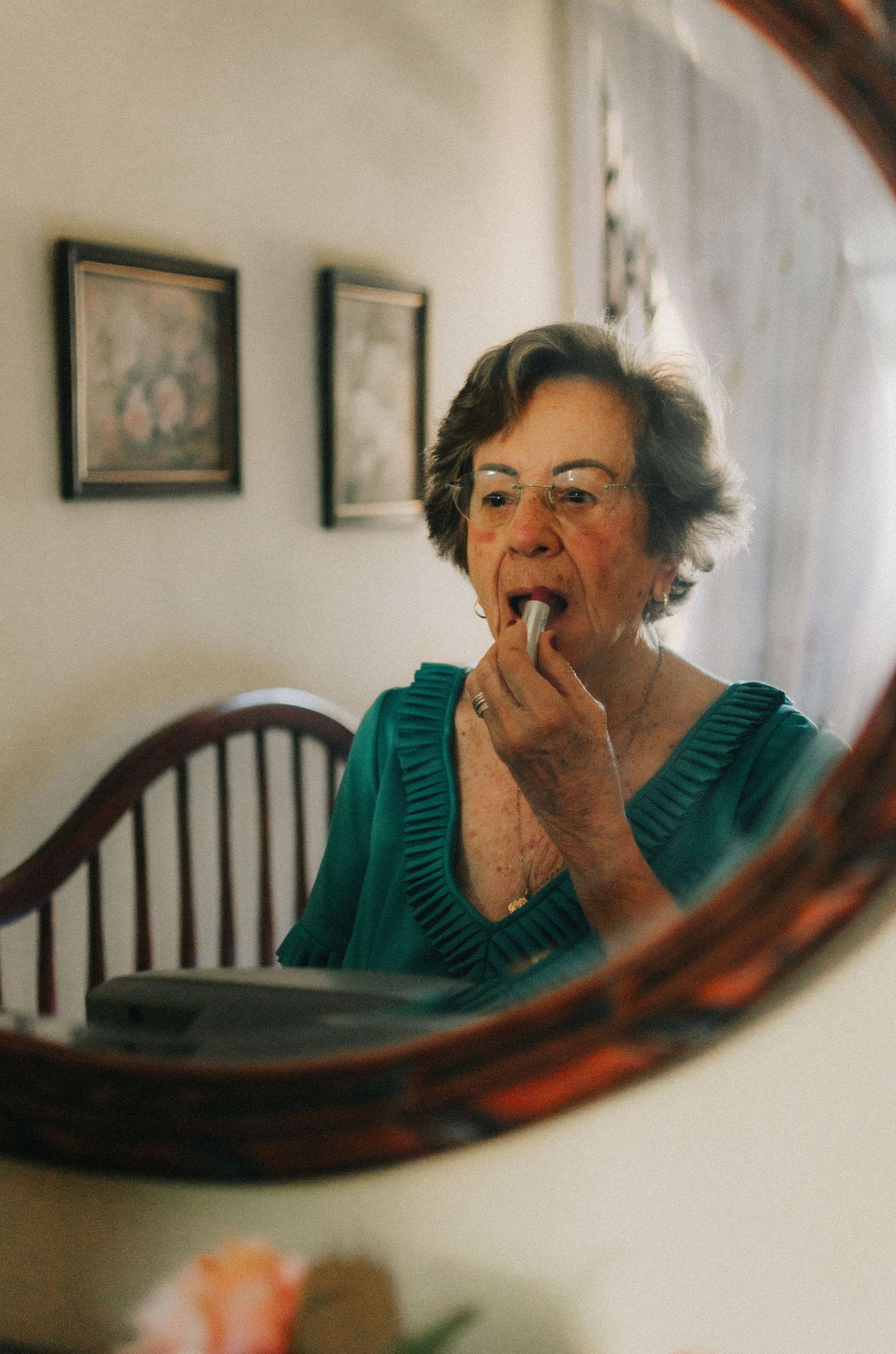 A sequence of four photos showing a person in a teal sweater yawning while reflected in a curved wooden mirror.