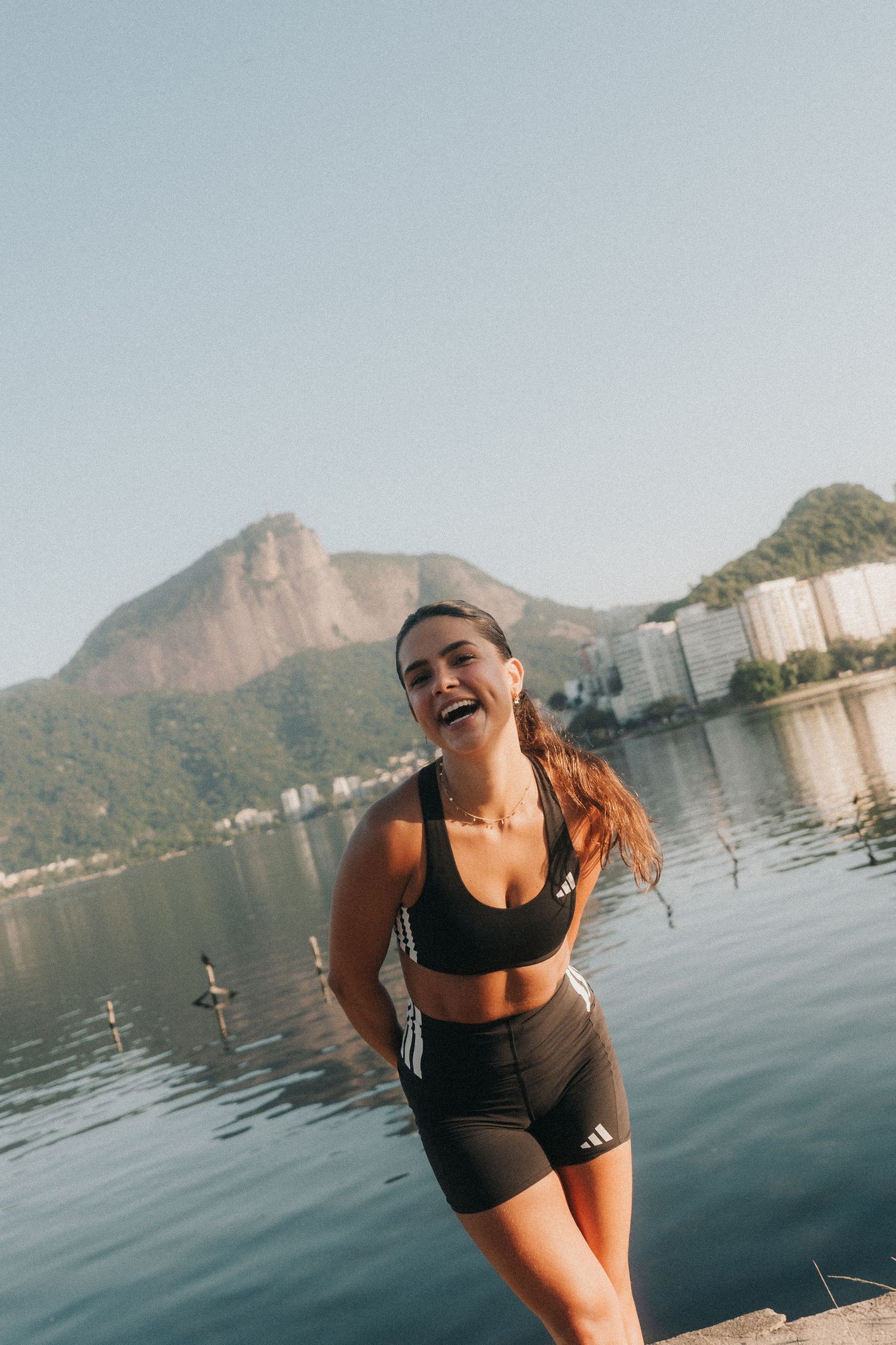 Person enjoying sunny day by water with scenic mountain backdrop and urban landscape in Rio de Janeiro.